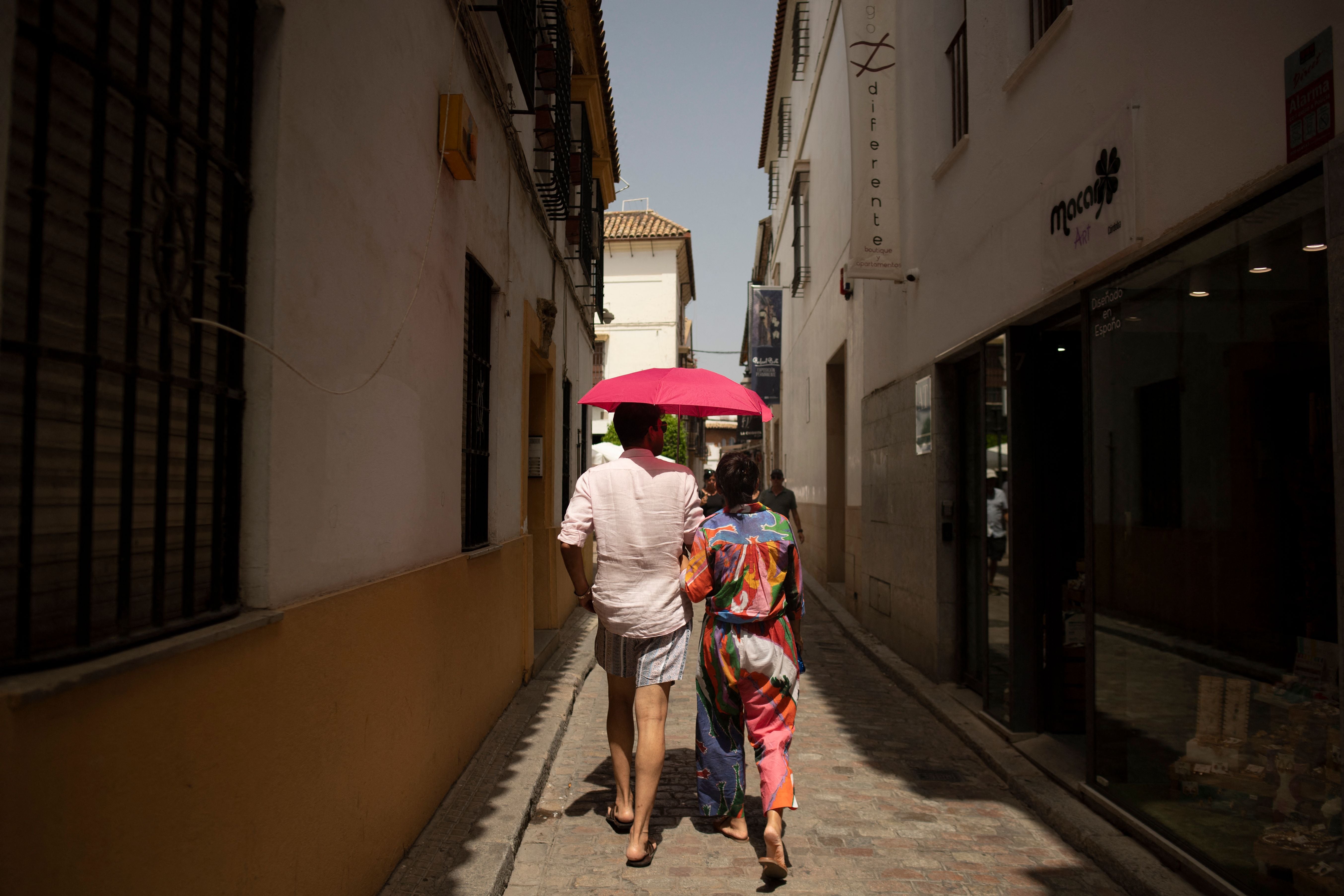 Tourists protect themselves from the sun using an umbrella during a heatwave in Cordoba in Cordoba, southern Spain