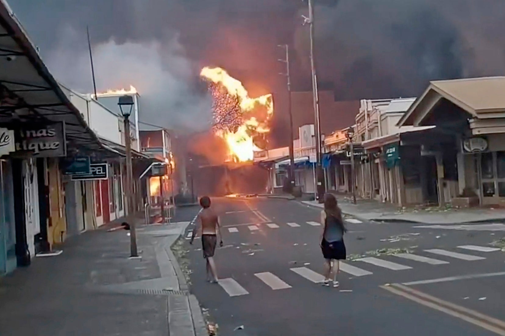 People watch as smoke and flames fill the air from raging wildfires on Front Street in downtown Lahaina