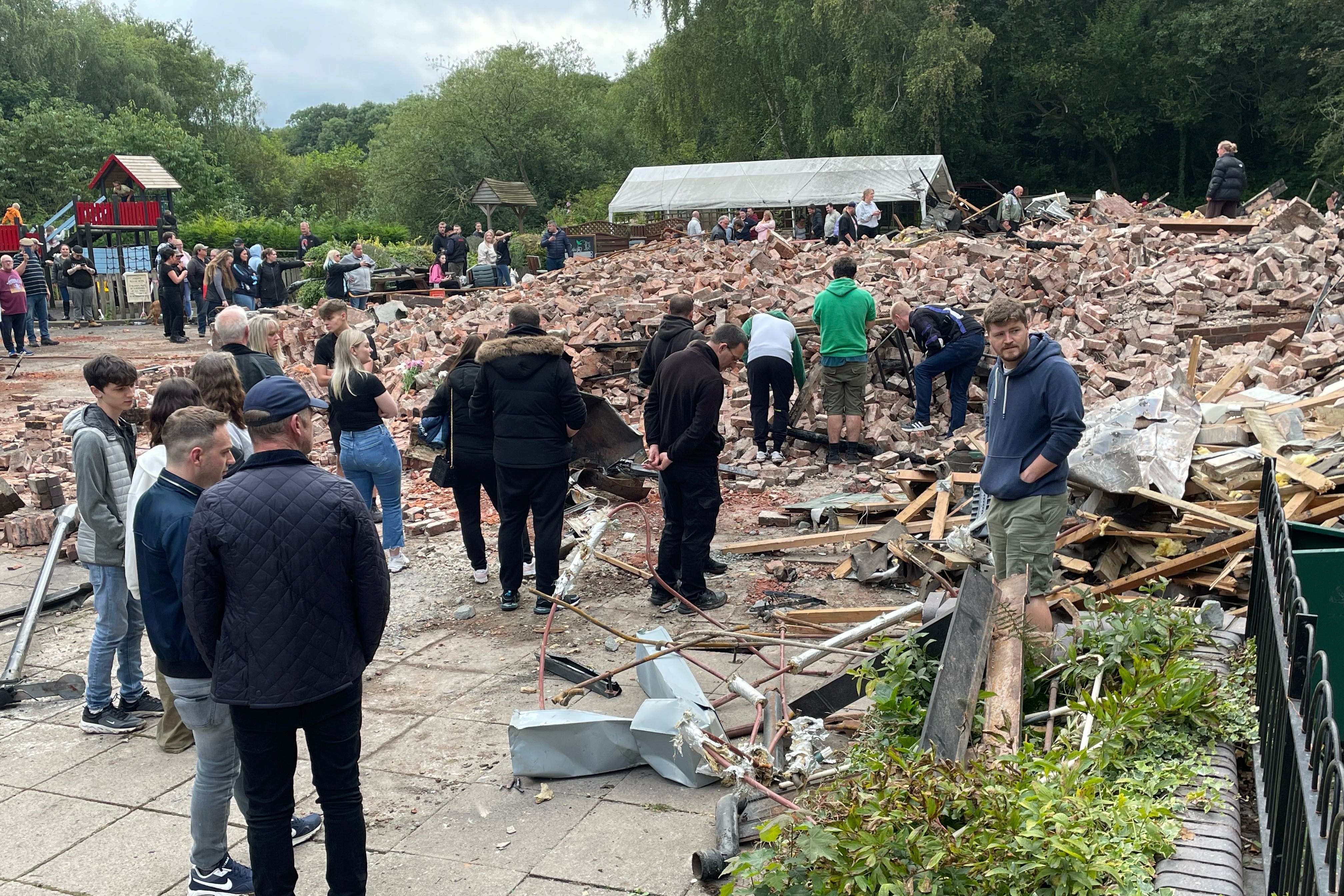 People inspect the rubble at The Crooked House pub (Matthew Cooper/PA)