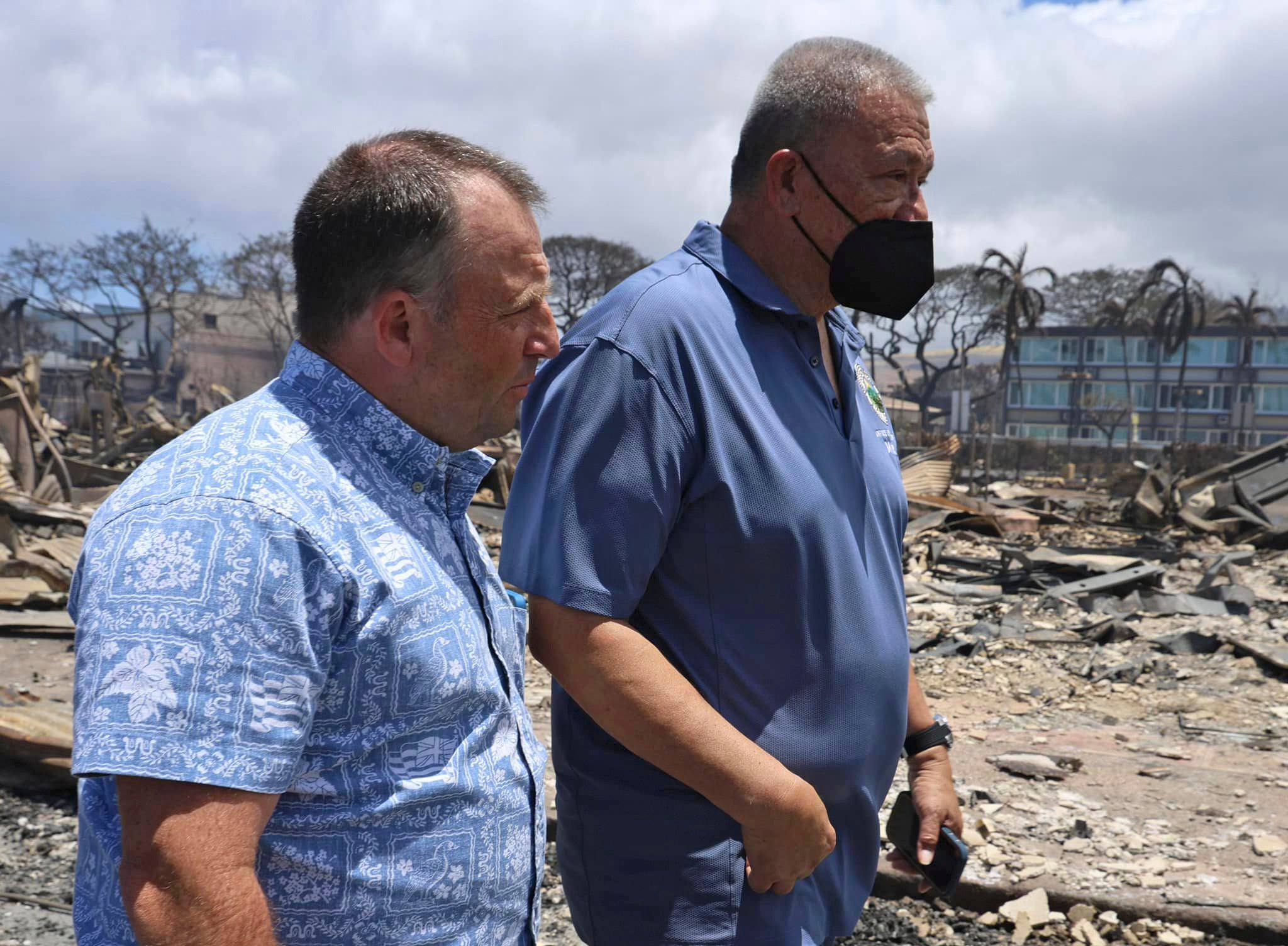 Hawaii Governor Josh Green, left, and Mayor Richard Bissen walk past the burned remains along Front Street in Lahaina