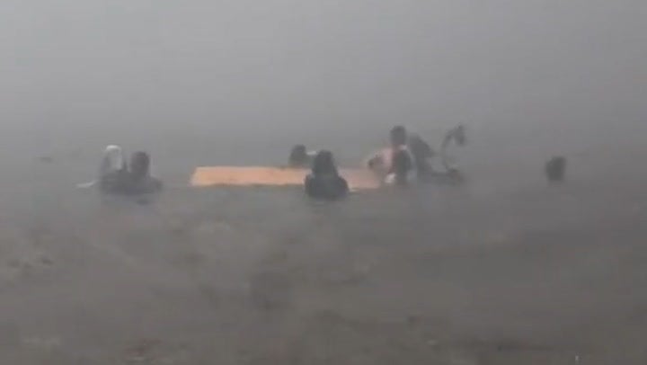 Survivors cling to a piece of wood after hurling themselves into the ocean to escape the Lahaina fires