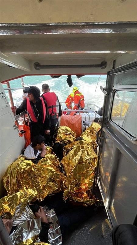 Rescued migrants sit on the ‘Notre Dame du Risban’ after a migrant boat trying to cross the Channel from France capsized