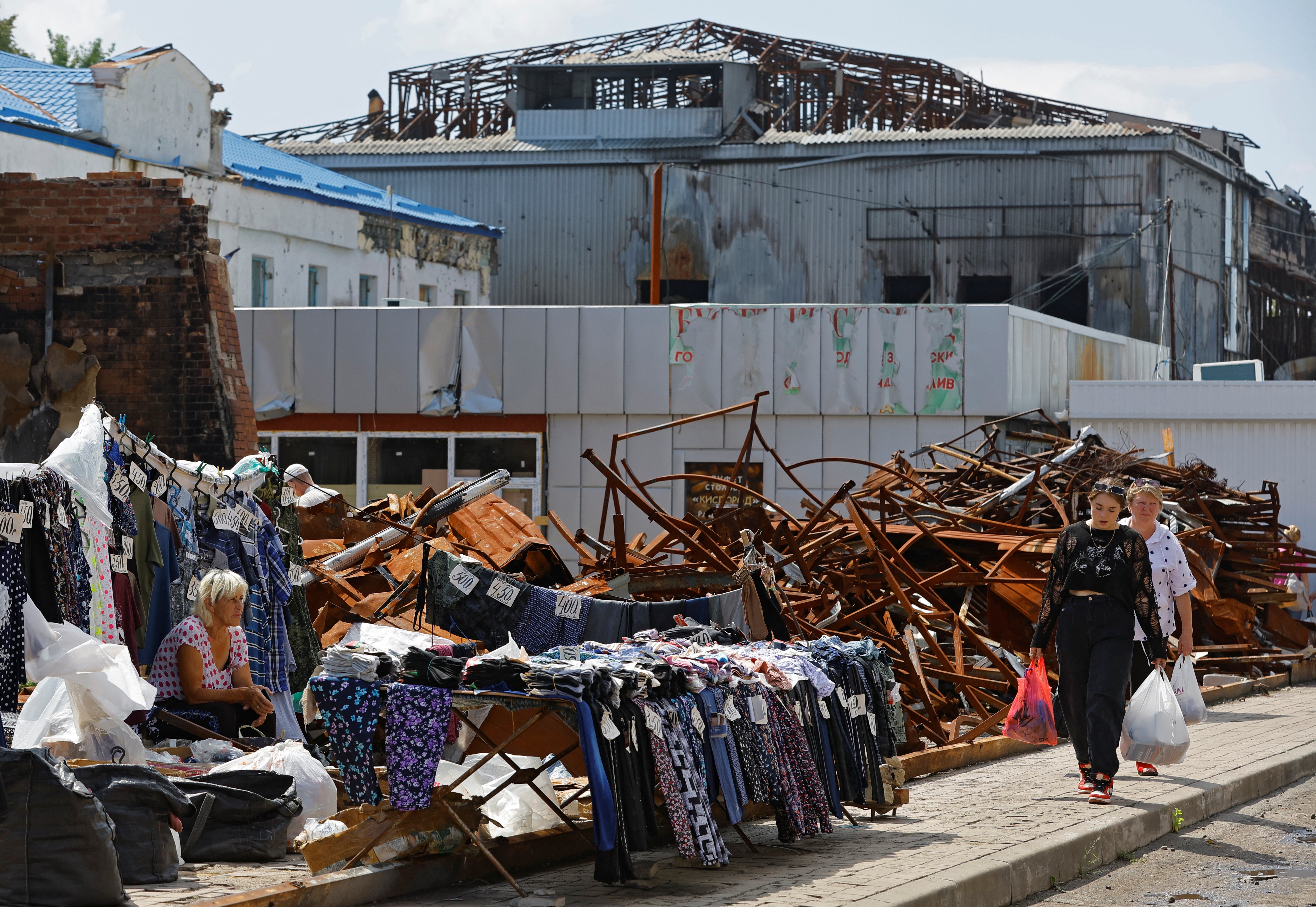 Shoppers continue about their business at a market damaged by airstrikes