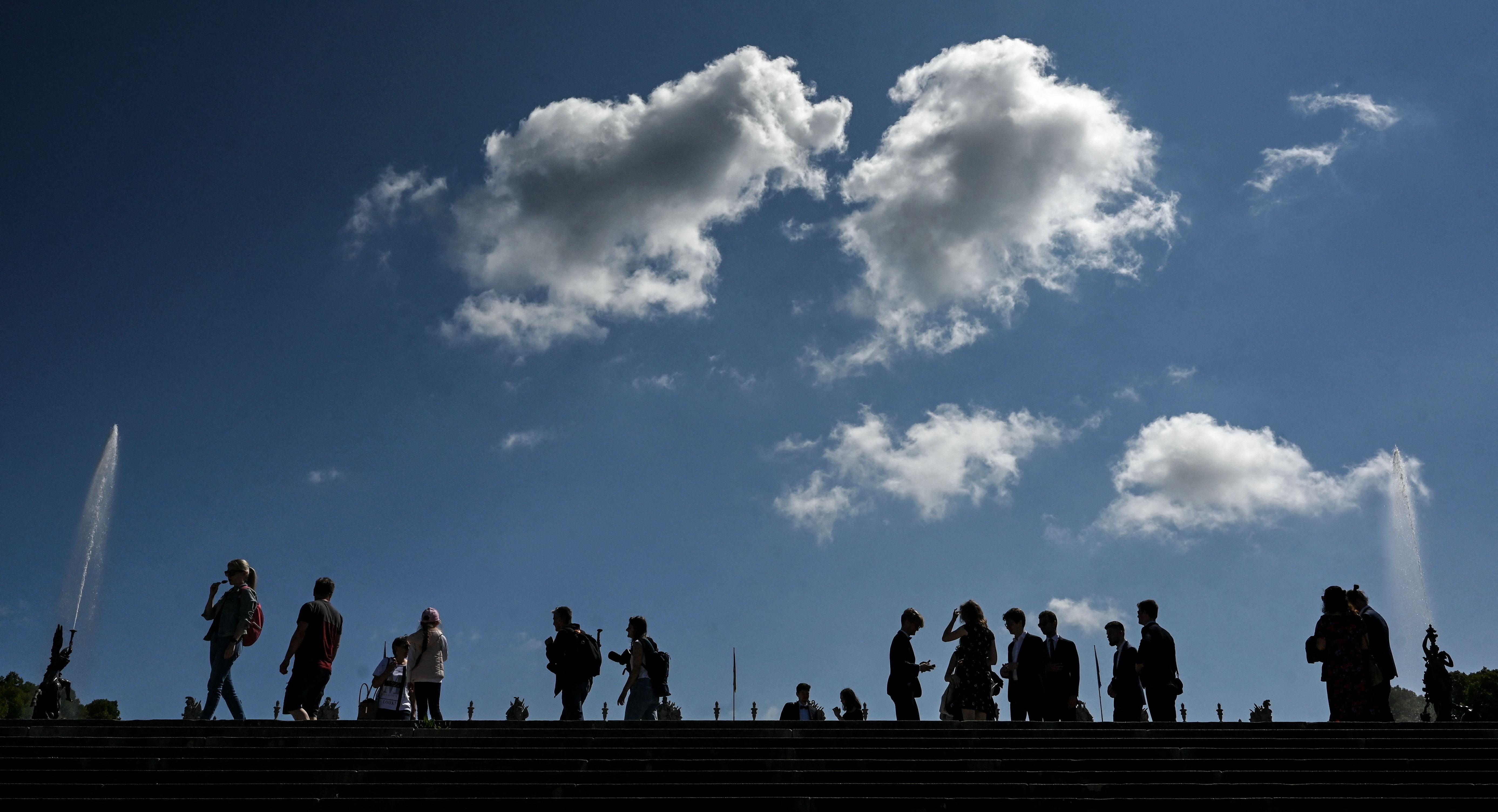 People enjoy the sunny weather on the steps in front of the Neues Schloss of Herrenchiemsee, pictured at the Herrenchiemsee island near Prien, southern Germany, on 10 August 2023