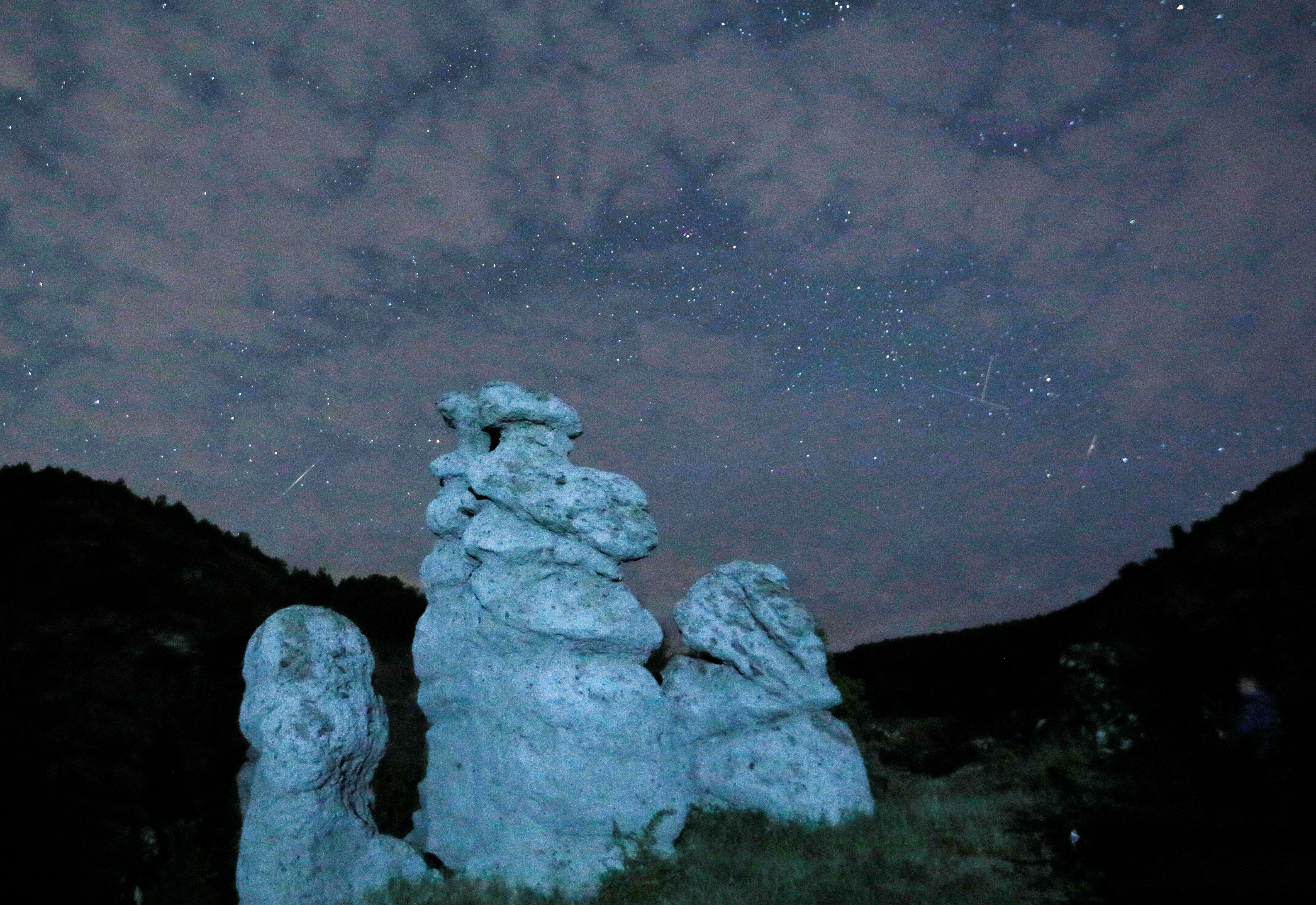 A meteor streaks during the Perseid meteor shower in the night sky over the village of Kuklici