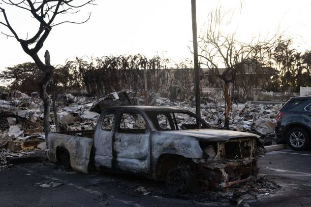 A burnt out car lies in the driveway of charred apartment complex in the aftermath of a wildfire in Lahaina, western Maui, Hawaii on 12 August