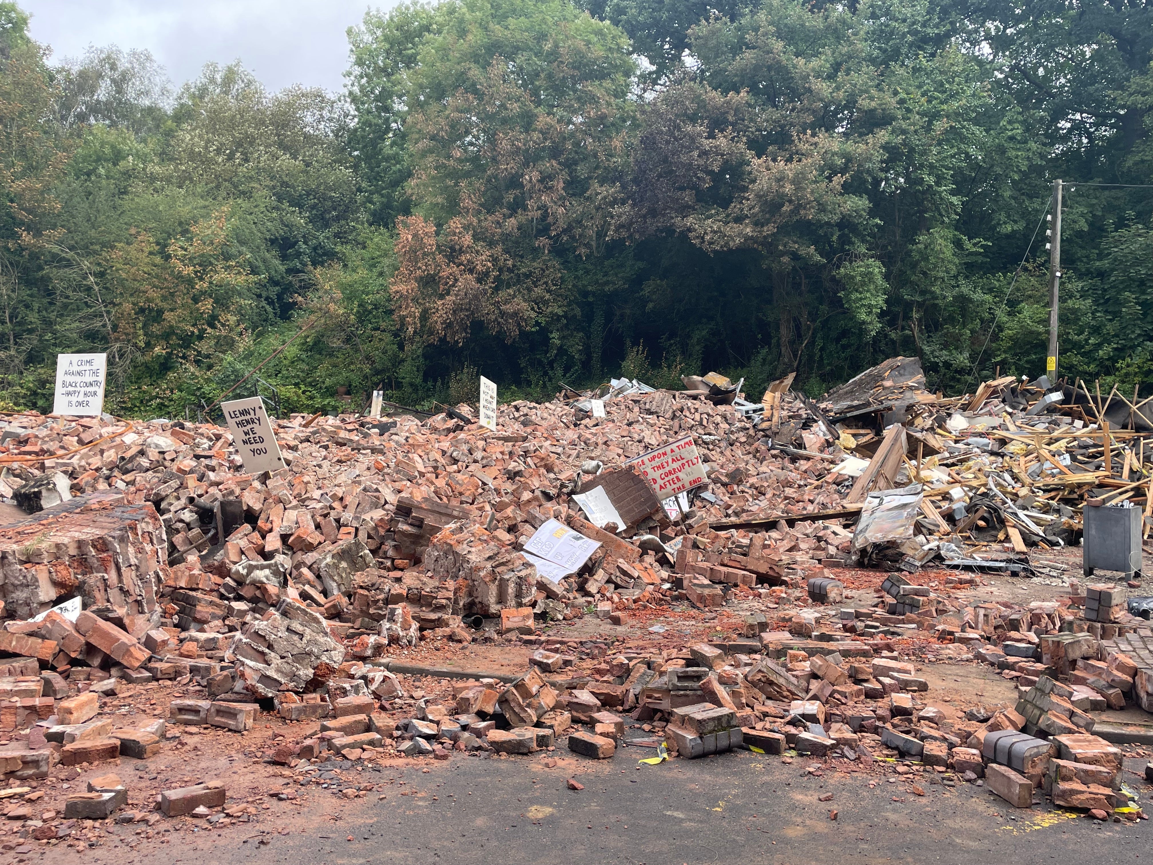 Signs are placed around what remains of The Crooked House pub