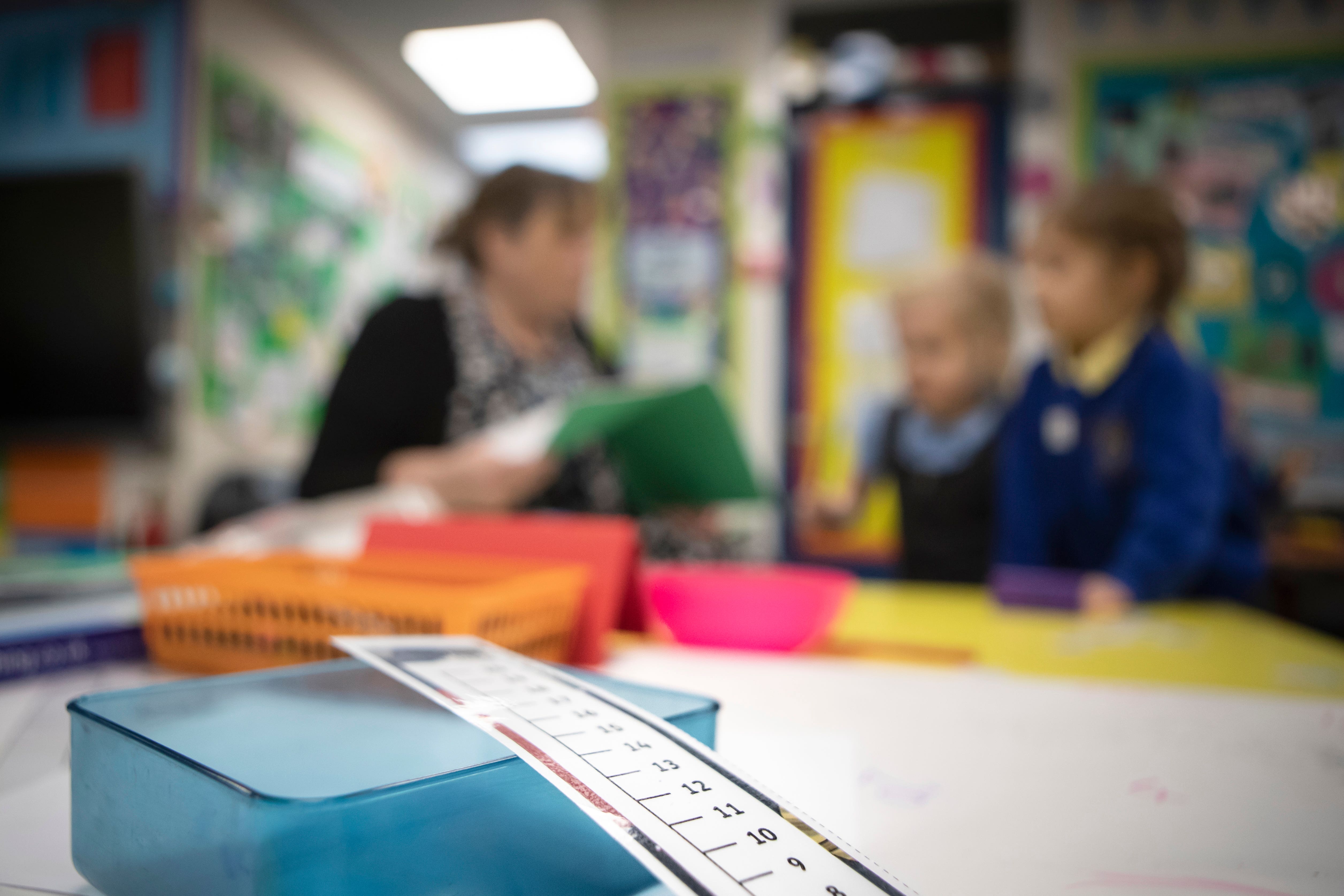 A teacher sits with two class pupils (Danny Lawson/PA)