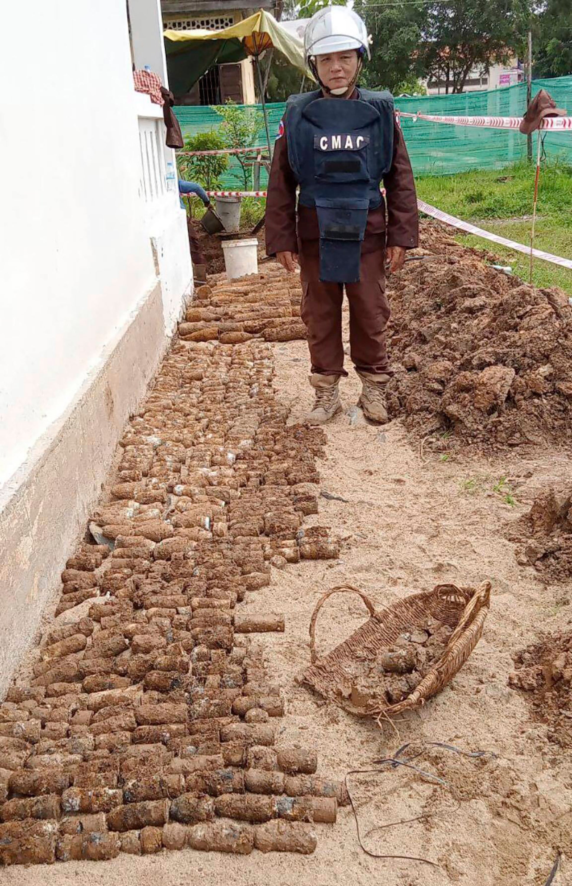 A deminer expert stands near a pile of unexploded ordnances at Queen Kossamak High School on 13 August