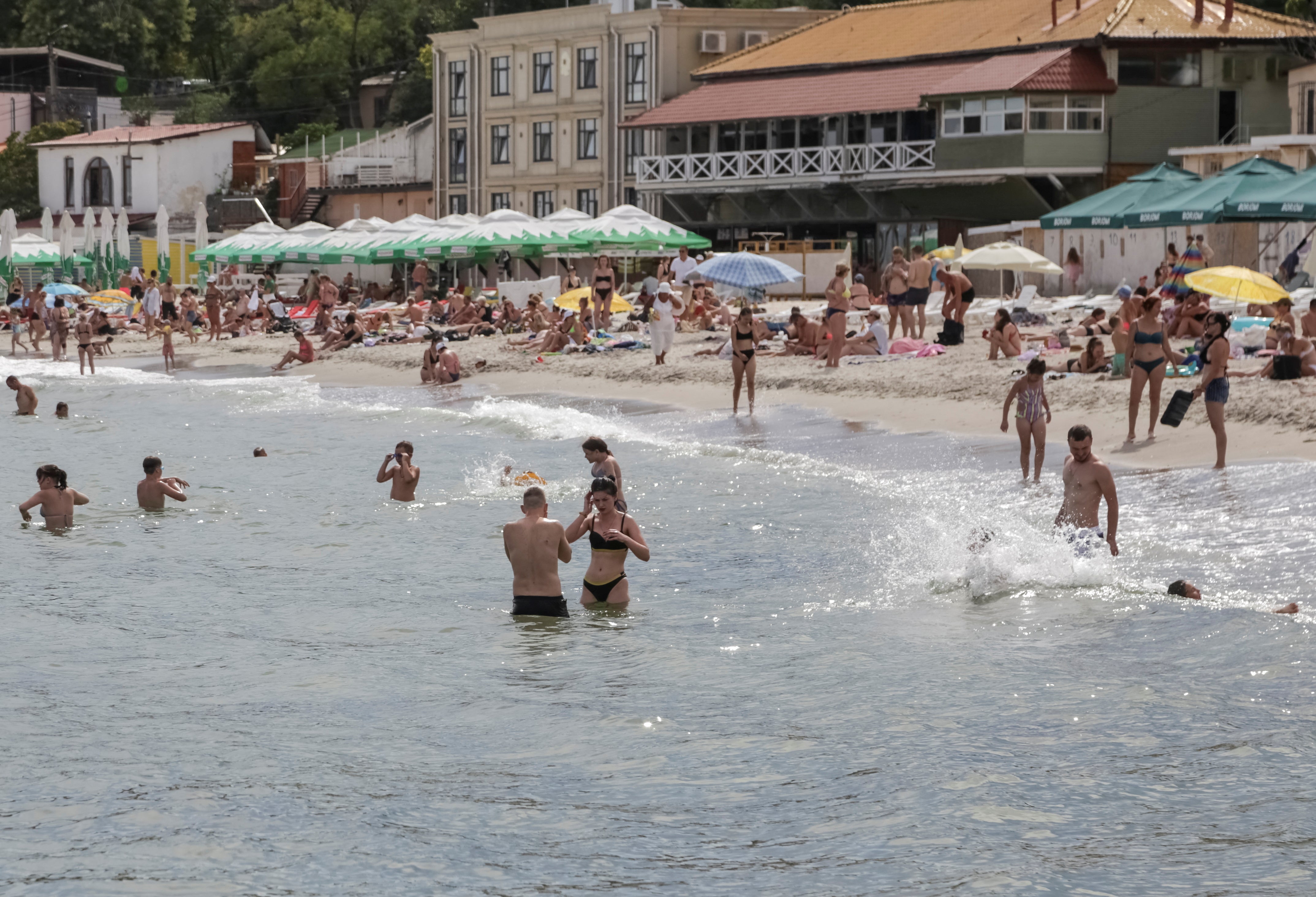 People relax at a Black Sea beach that was reopened after being closed down last year following sea mines laid around the ports of Odesa and Mykolaiv by Russia and Ukraine