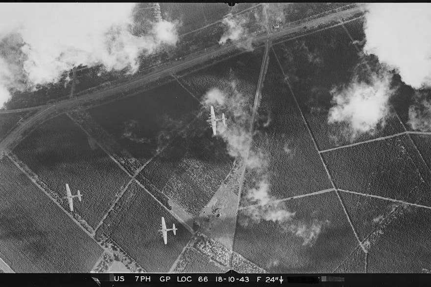 This vertical aerial photograph looks down through a break in the clouds on Eighth Air Force B-17 bombers flying over The Brecks area of Norfolk. Identification marks on the wings suggest they belong to a Bomb Group within the 3rd Air Division (Historic England Archiv/USAAF Photography/PA)