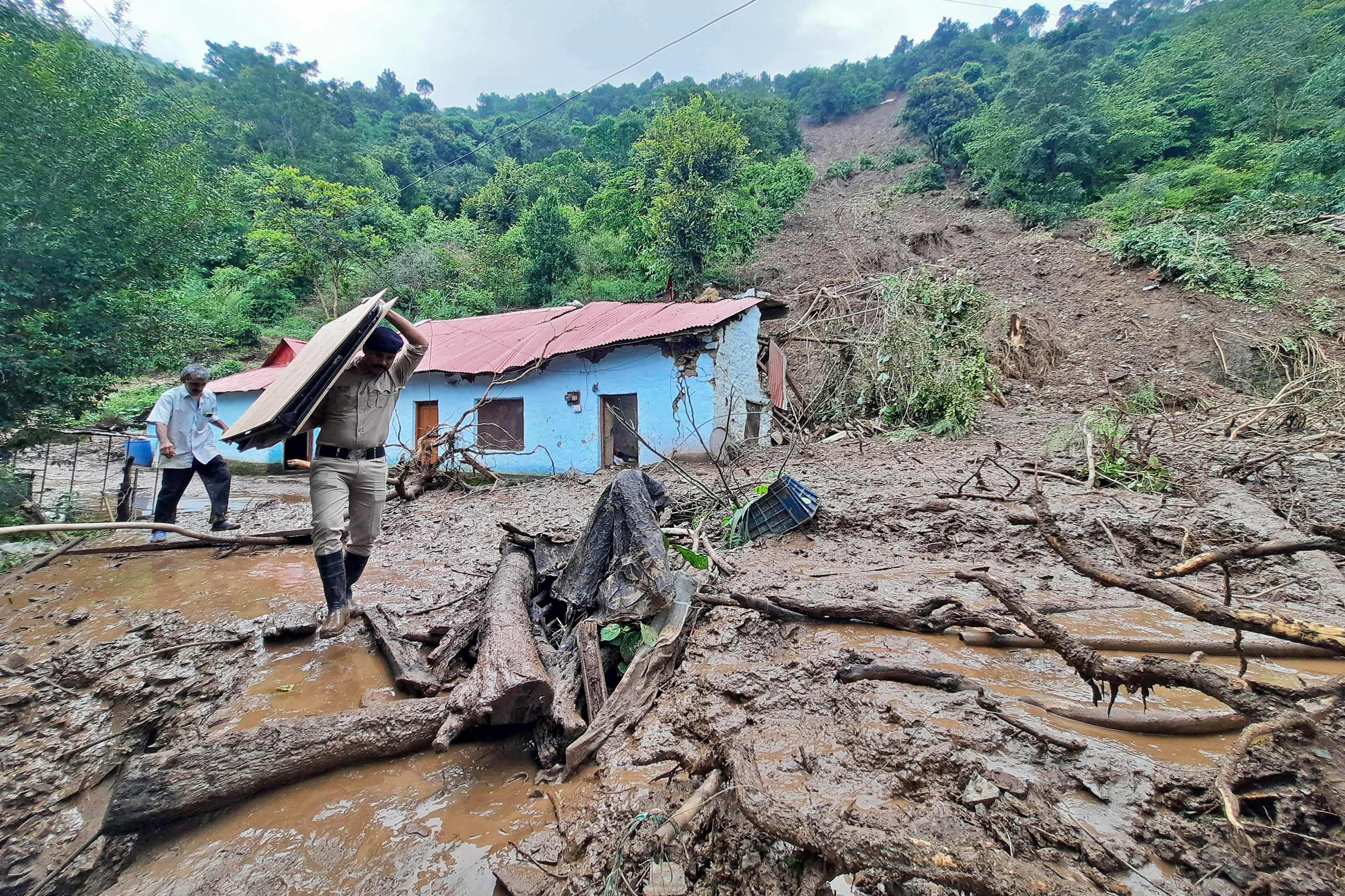 A security personnel carries the belongings of a villager from the site of a landslide after heavy rains at Jadon village in Solan district of India’s Himachal Pradesh