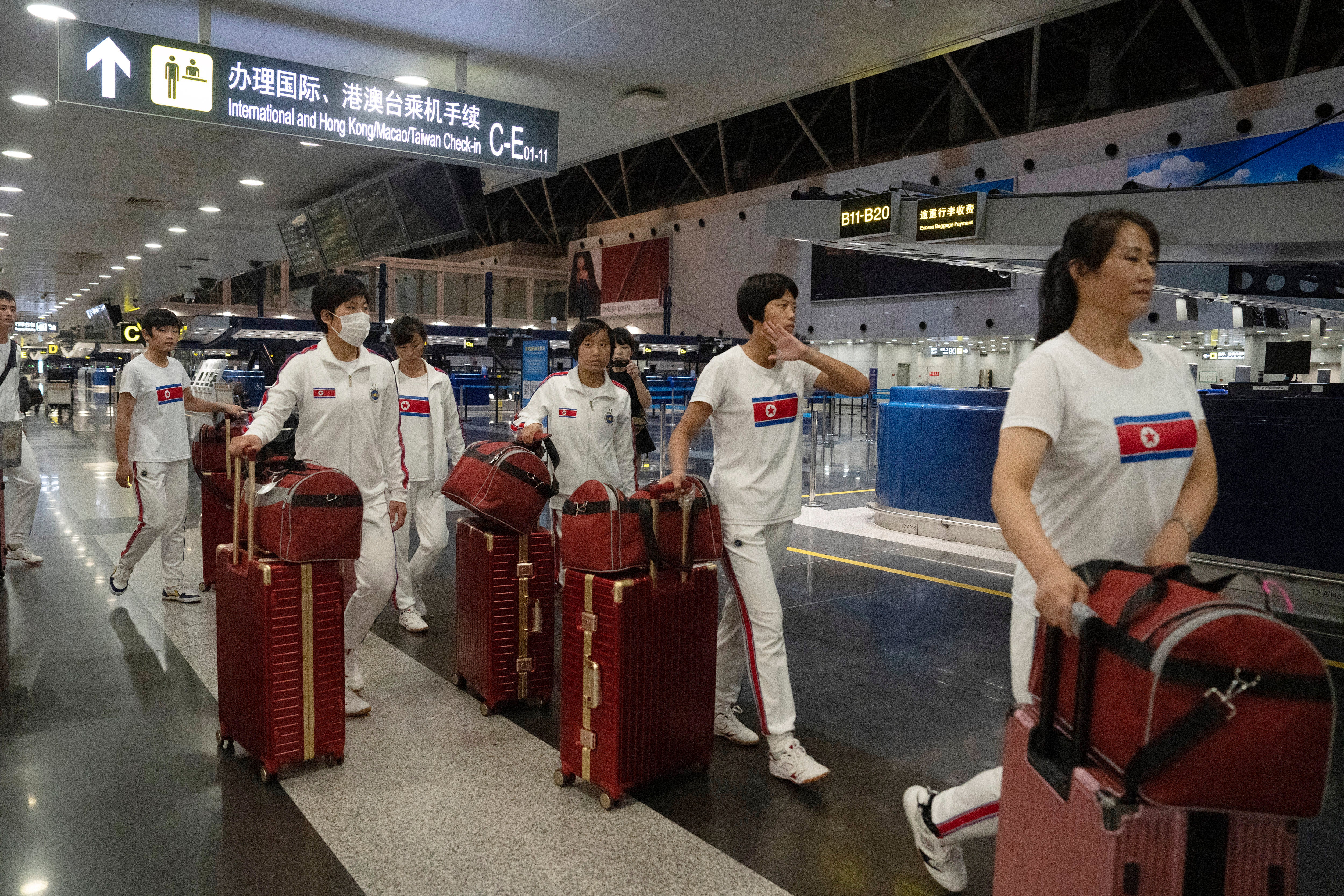 North Korean women wearing track suits with the North Korean flag and the words Taekwon-Do printed on the back walk to check in for a flight to Astana at the Capital Airport in Beijing, Friday, Aug. 18, 2023
