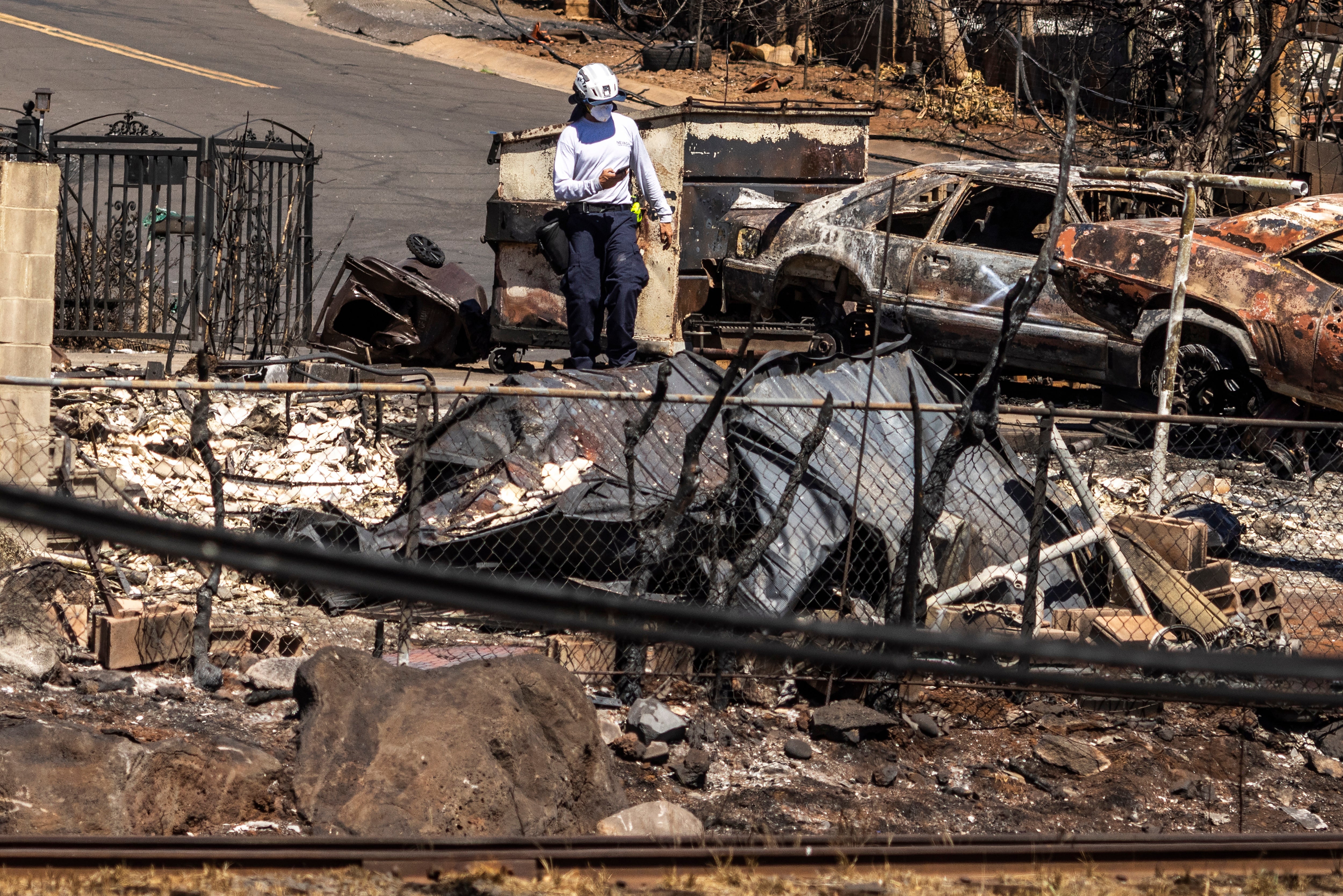 An urban search and rescue crew member searches for human remains at a home destroyed by the West Maui Fire, in Lahaina