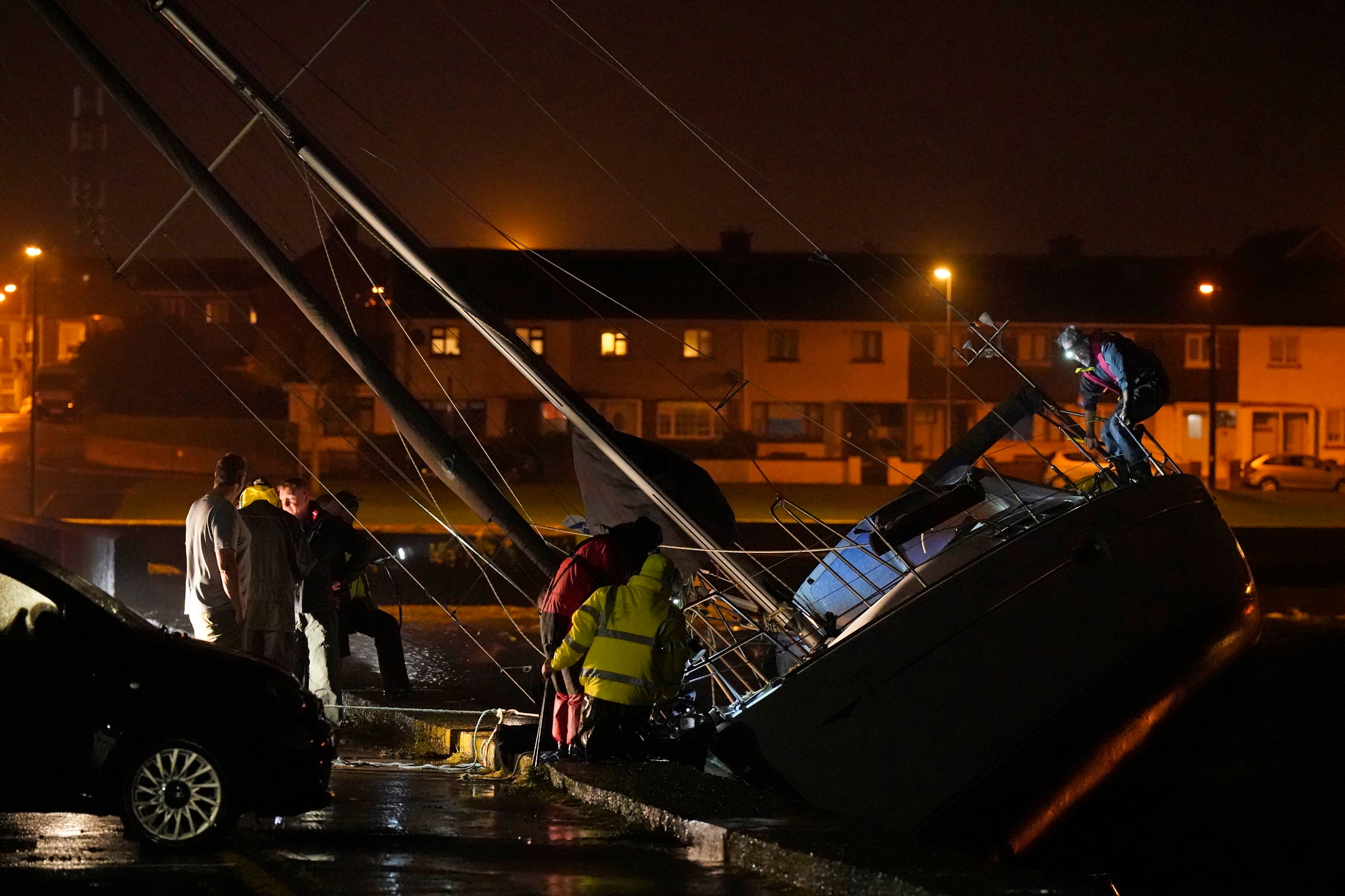 Members of the Coast Guard inspect the damage to a boat after it broke free from its berth and crashed into the harbour during Storm Betty in Dungarvan, County Waterford