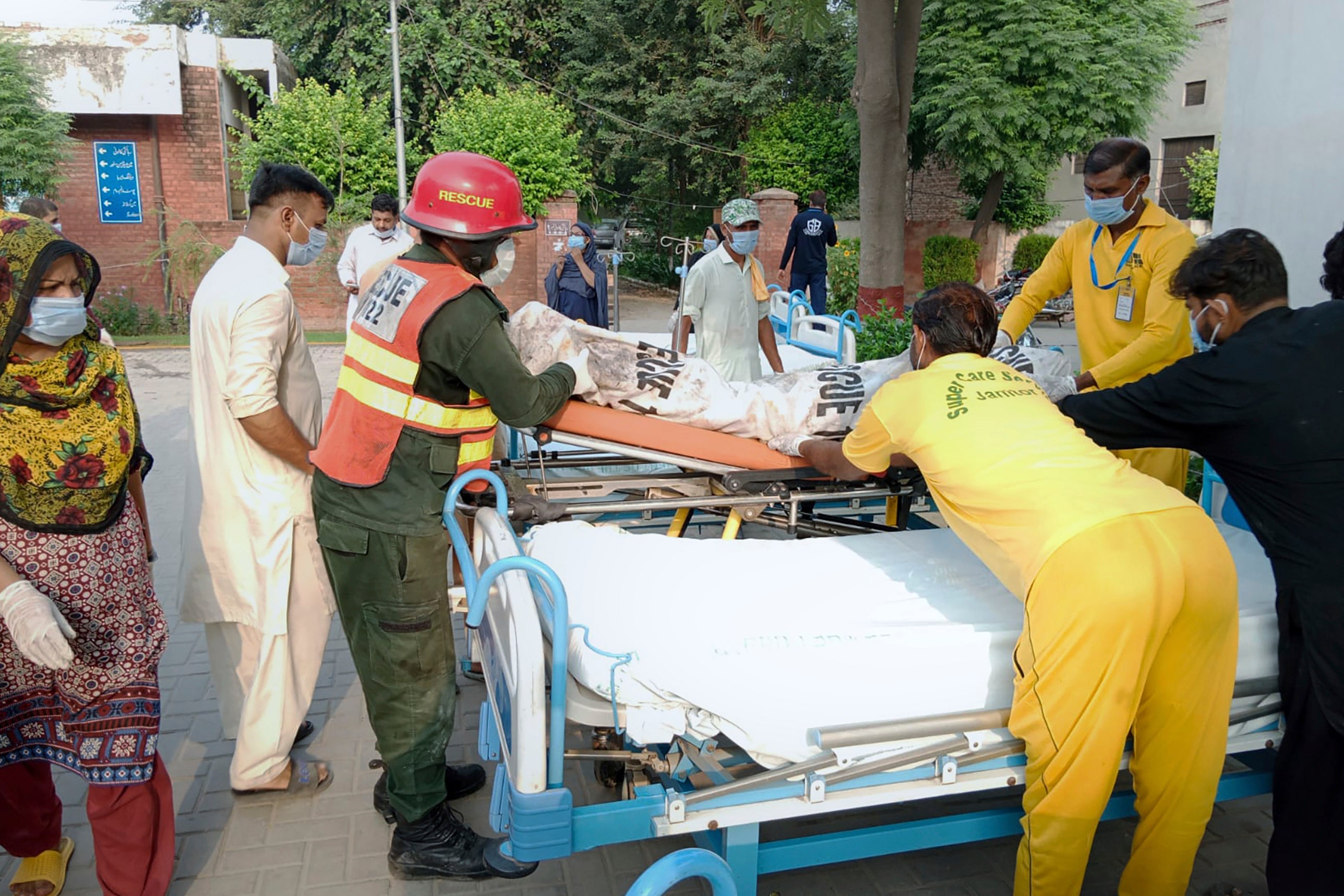 Hospital staff and rescue workers carry a victim of a bus accident into a hospital in Pindi Bhattian