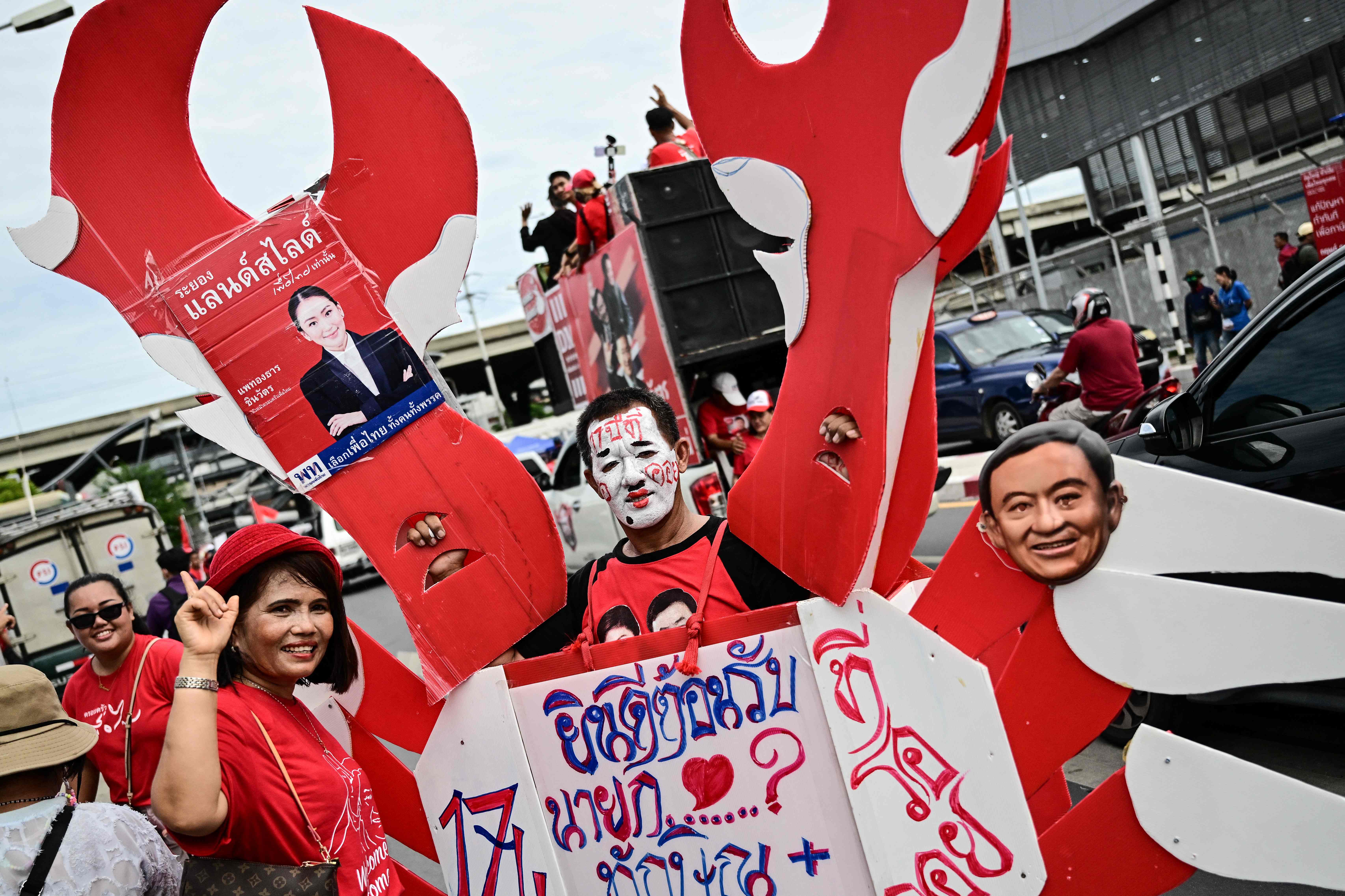 Supporters of Thaksin Shinawatra hold placards as they wait outside Bangkok’s Don Mueang airport