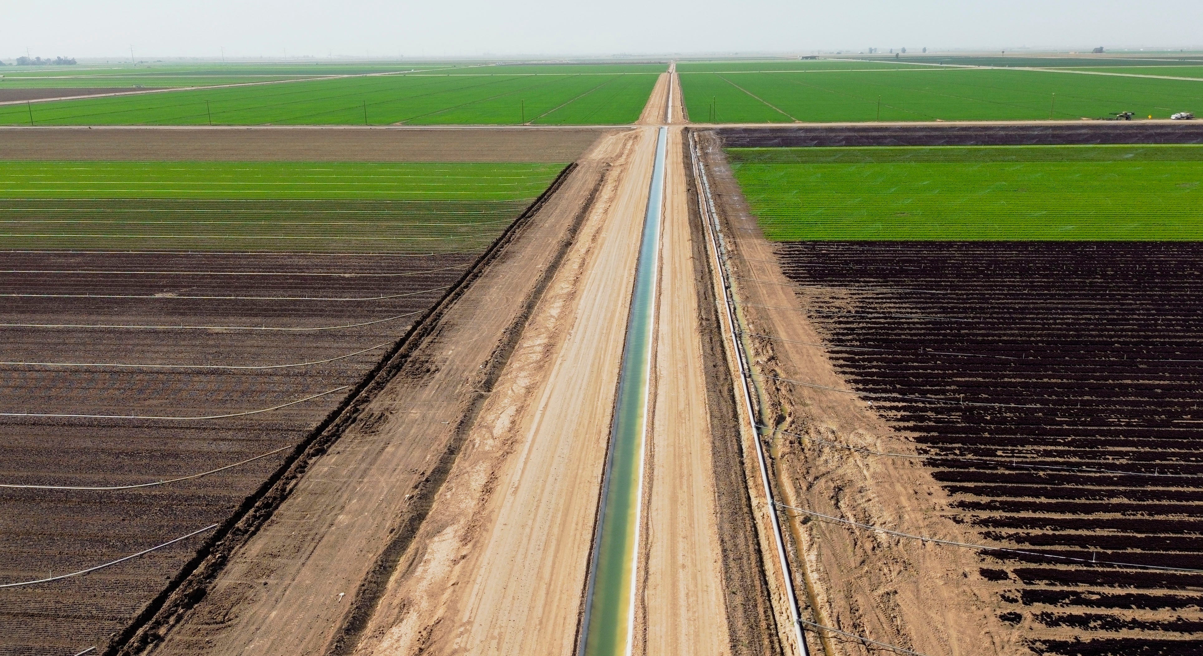 An irrigation canal cuts through farm fields in California. But reserves are being exhausted by agriculture