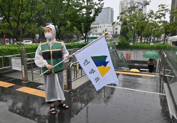 A South Korean government official holding a civil defence flag guides citizens into underground facilities after an air raid siren sounded during a civil defence drill against possible artillery attacks by North Korea in Seoul on 23 August 2023