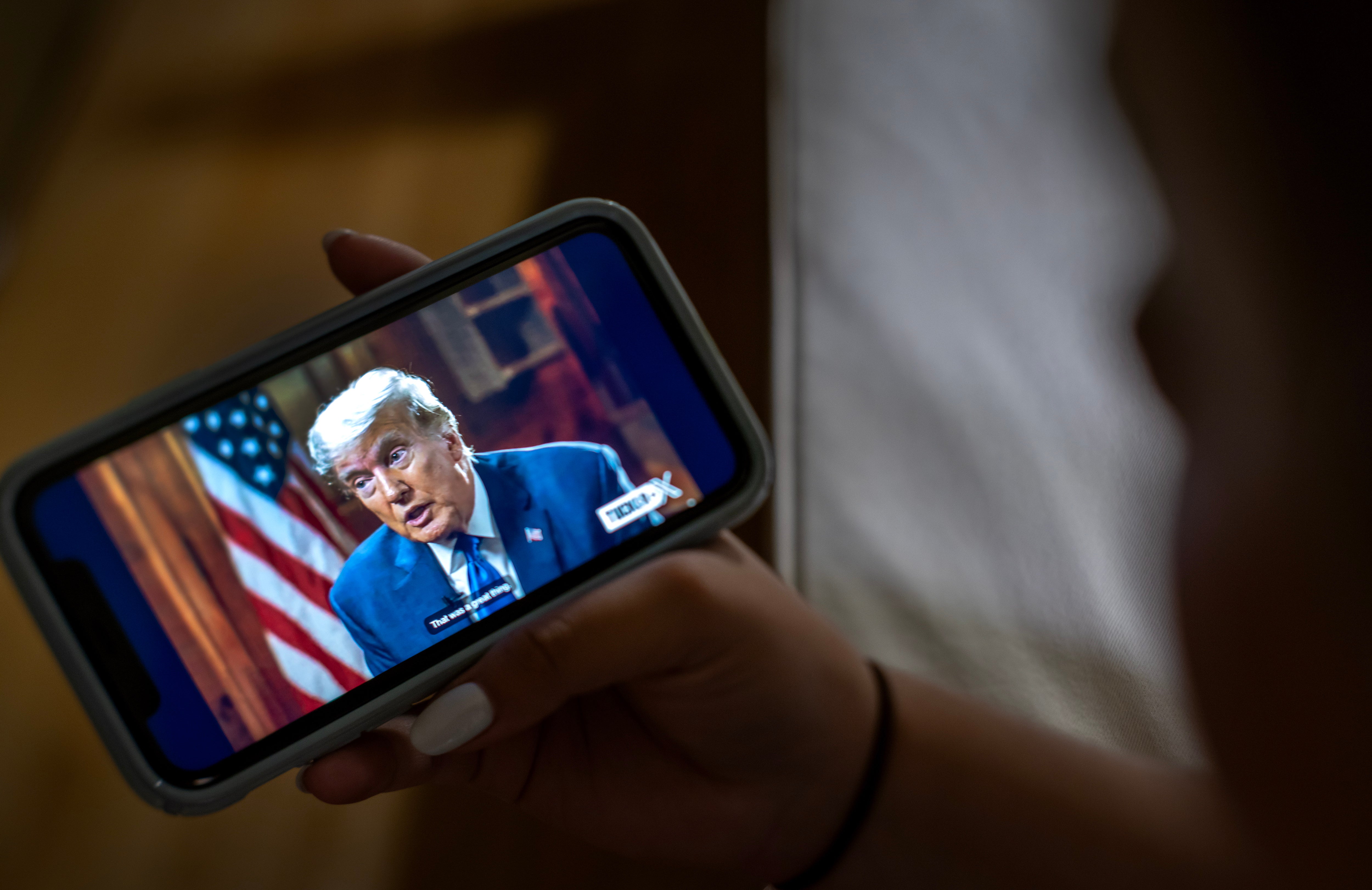 A viewer watches former President and Republican presidential candidate Donald Trump's interview by Tucker Carlson on the platform 'X' on their phone in Miami, Florida, USA