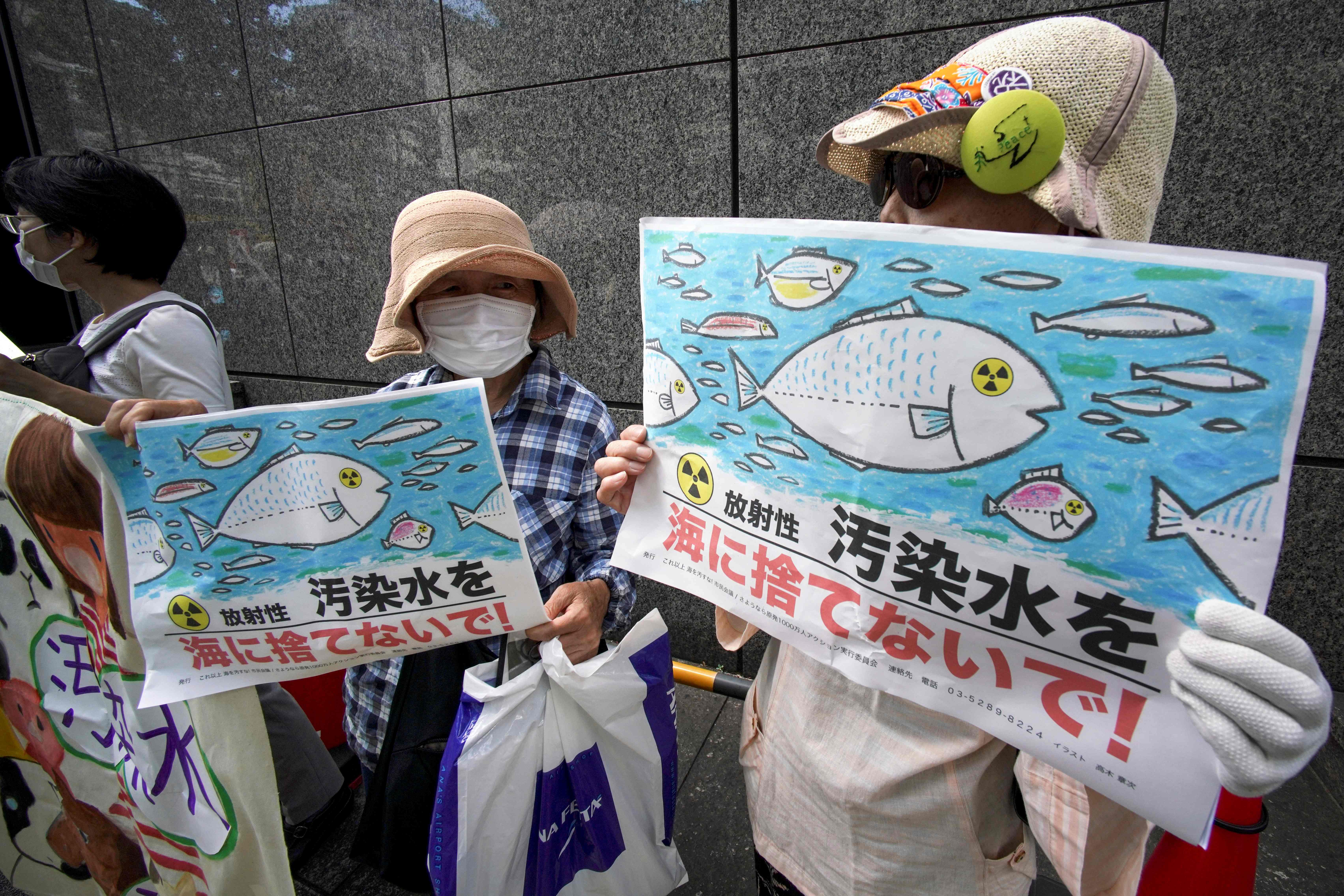 Protesters outside power company offices in Tokyo hold signs reading ‘Don’t throw radioactive contaminated water into the sea!’