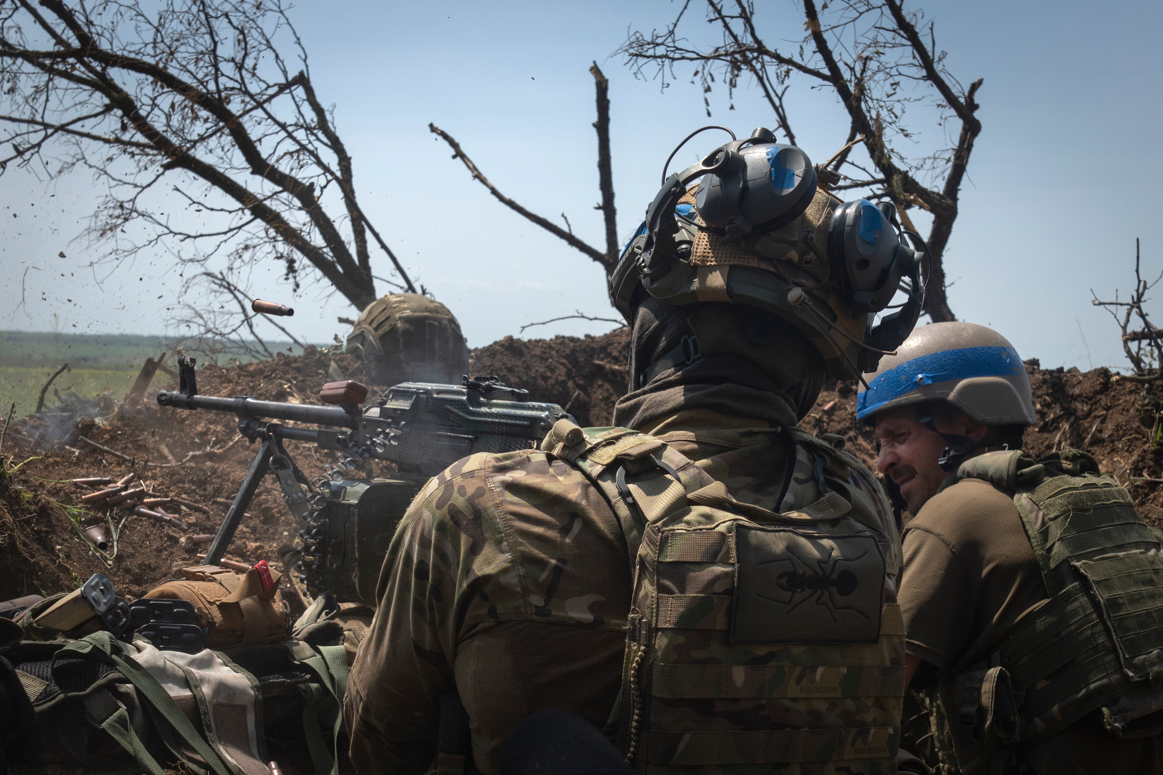 Ukrainian soldiers firing toward Russian positions from a trench on the front line in Zaporizhzhia in June