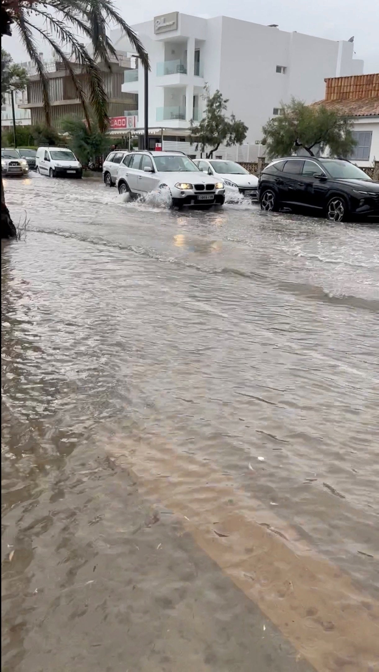 A view shows a car passing through a flooded road in Mallorca, Spain, August 27, 2023, in this screen grab obtained from a social media video