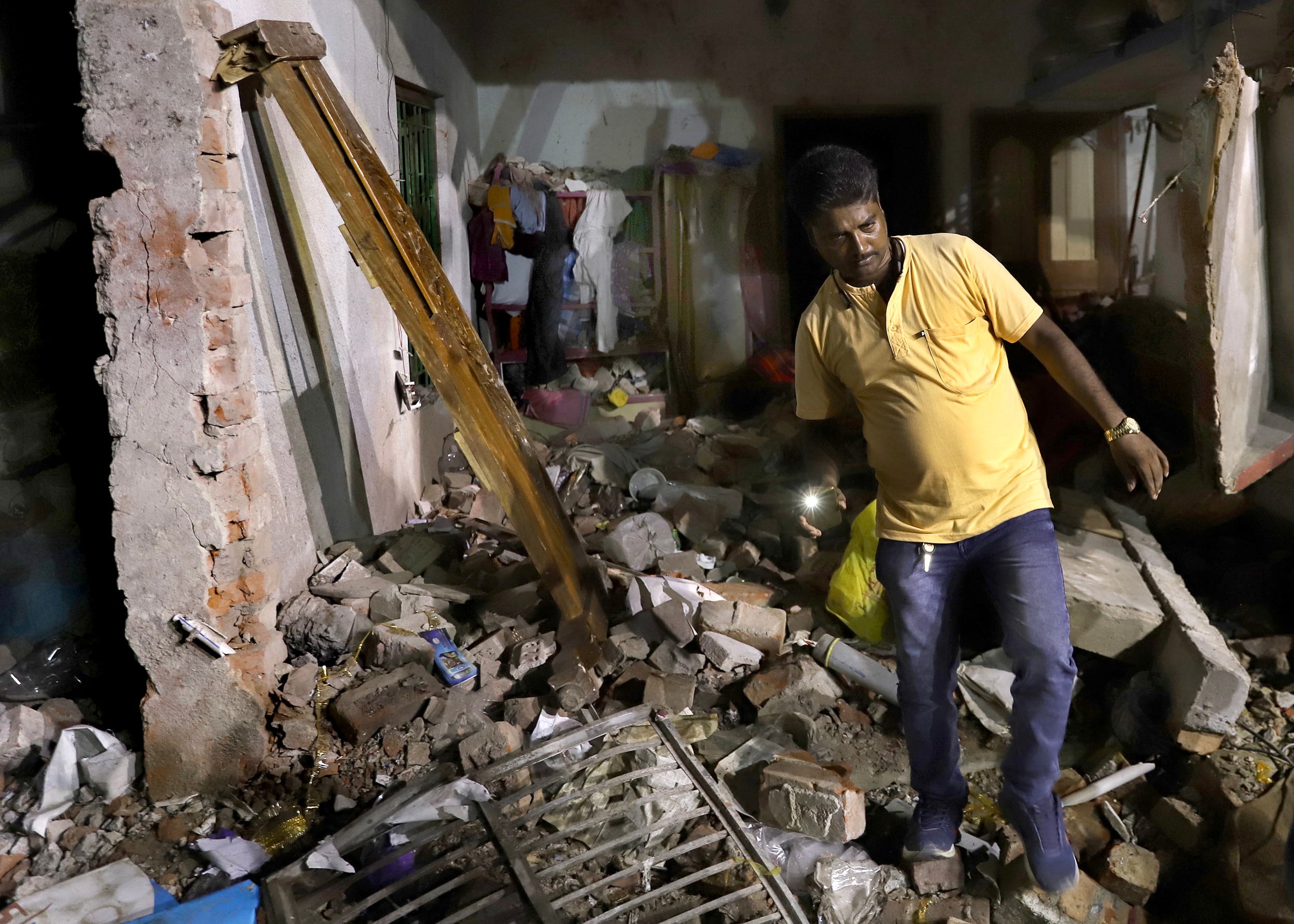 A resident inspects his damaged home after a massive explosion occurred at a firecracker factory in Duttapukur village, east of Kolkata, West Bengal state