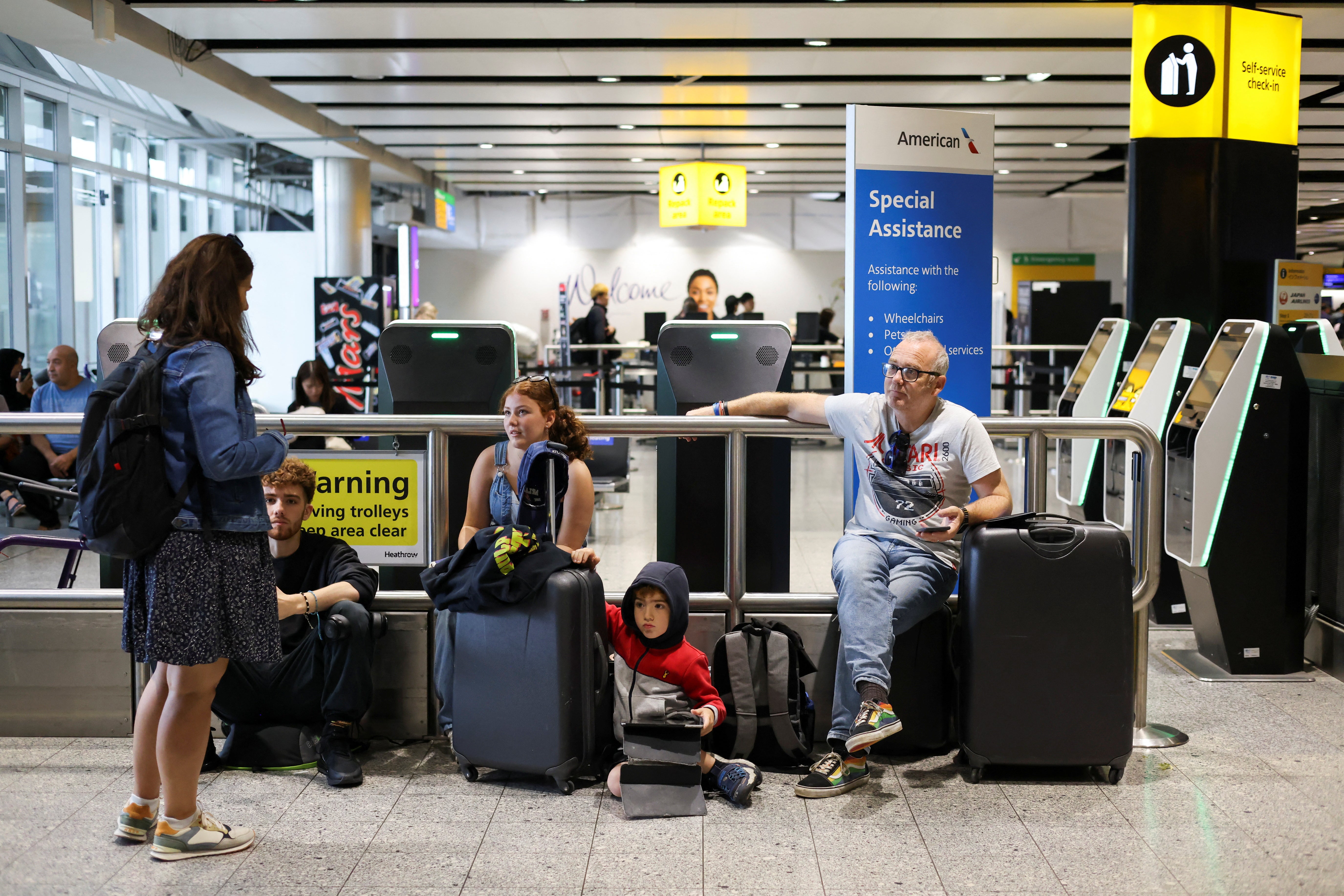 A family waits for flight information after the National Air Traffic Service (NATS) restricted air traffic