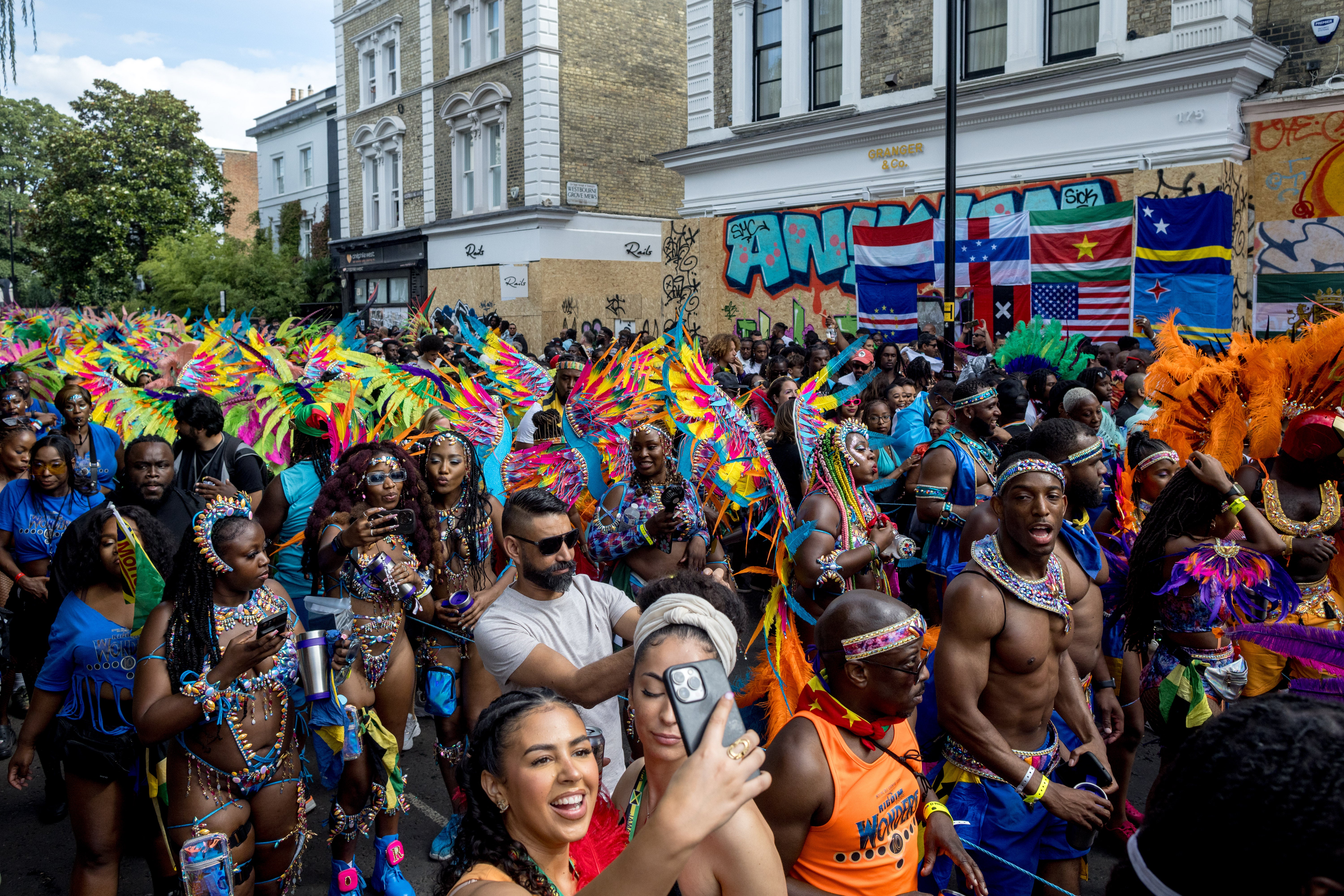 Revellers take pictures as performers parade in costume on the final day of Notting Hill Carnival