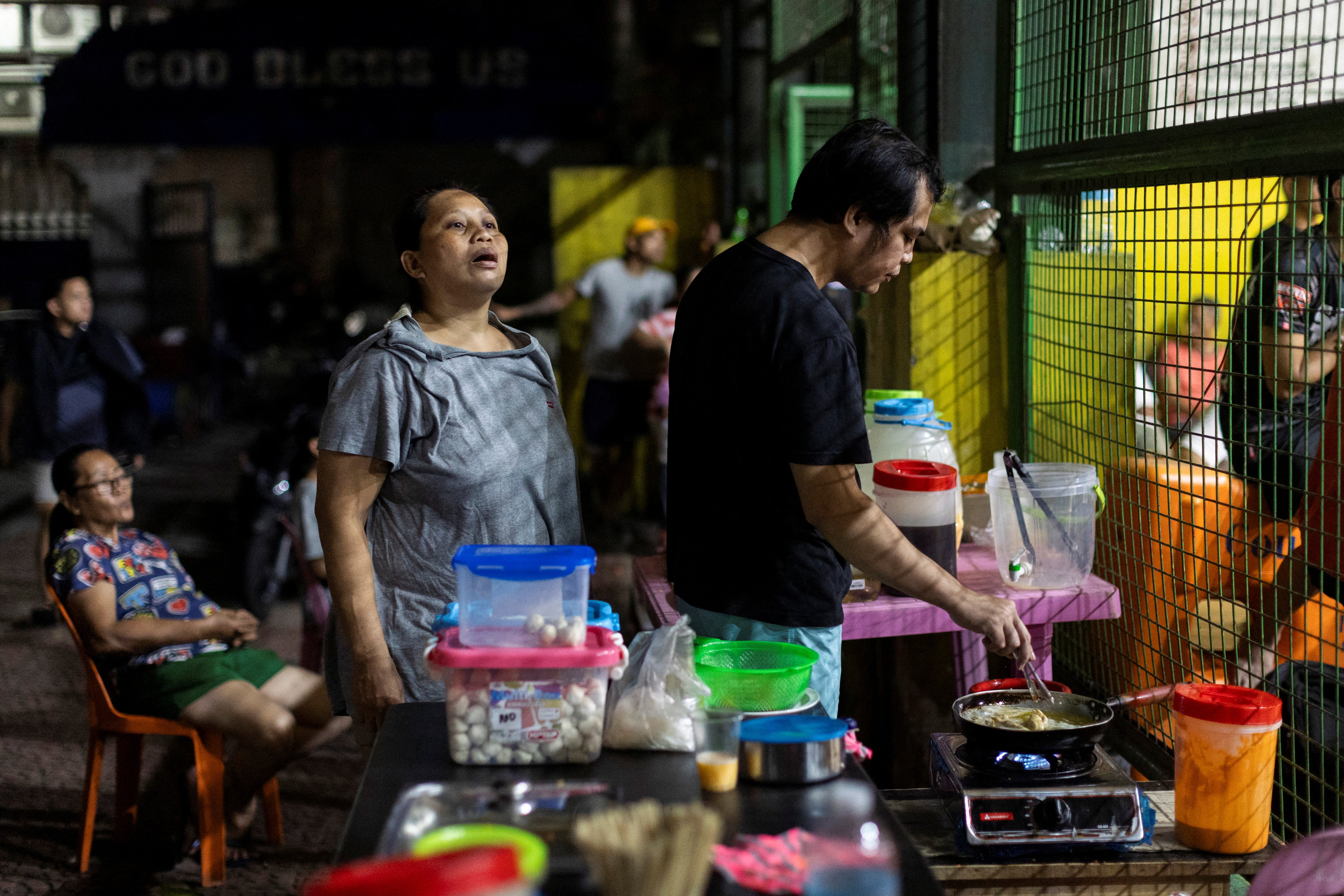 Snack vendors watch a community league basketball game from the sidelines at a basketball court in Quezon City, Manila