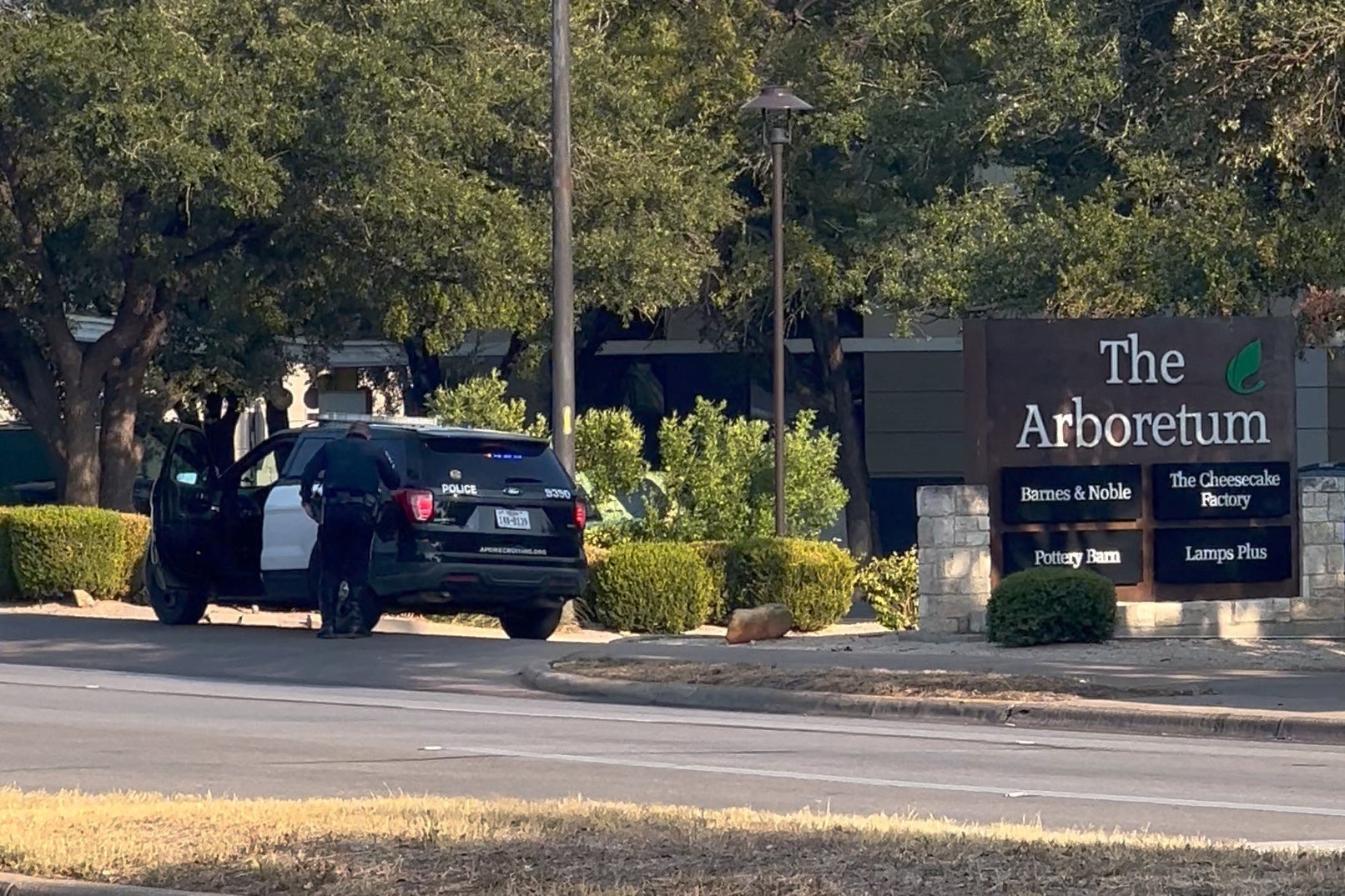 A police officer stands outside Arboretum Shopping Center following a shooting incident