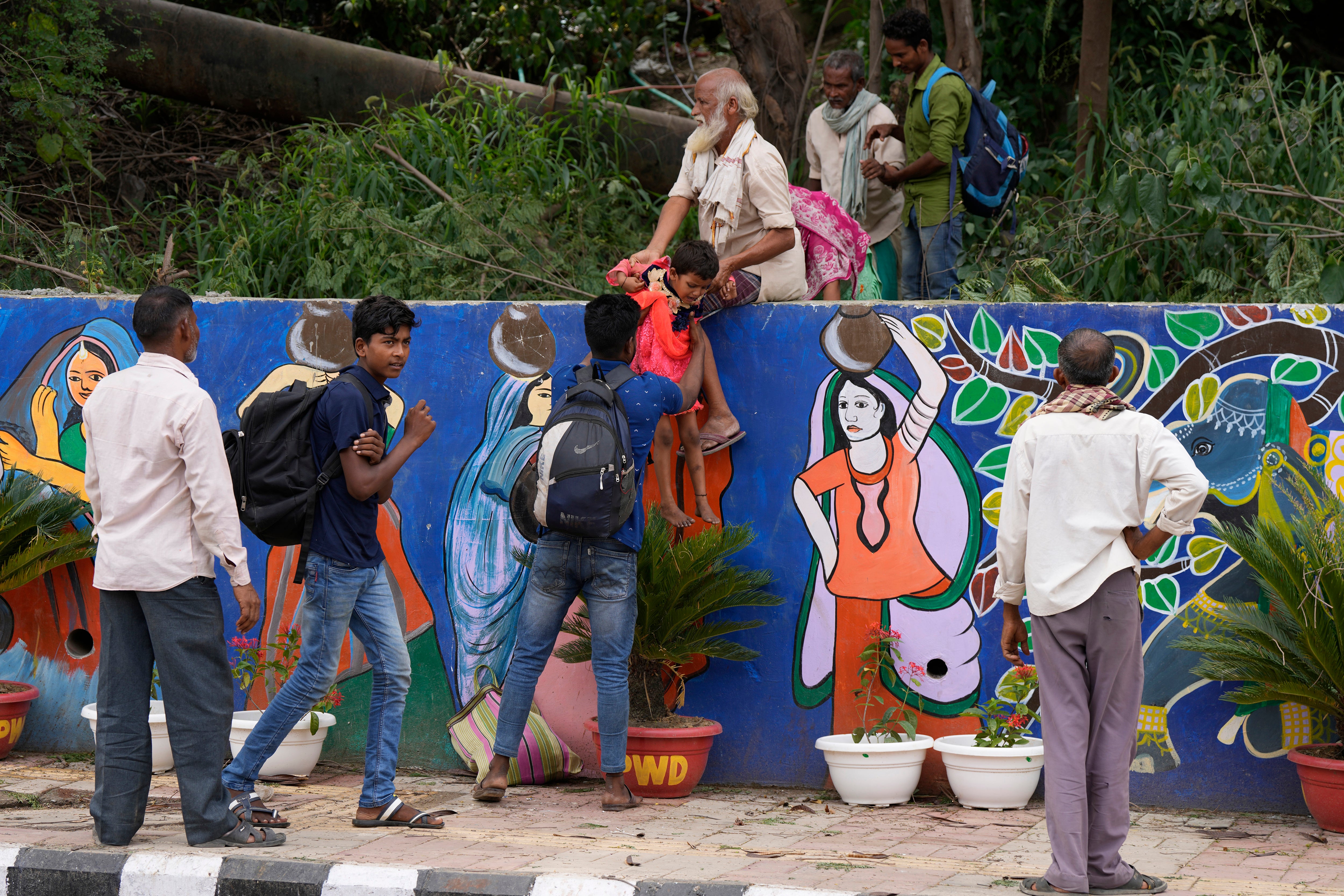 Migrant labourers climb over a wall, newly painted in preparation of the G20 summit, in New Delhi, India