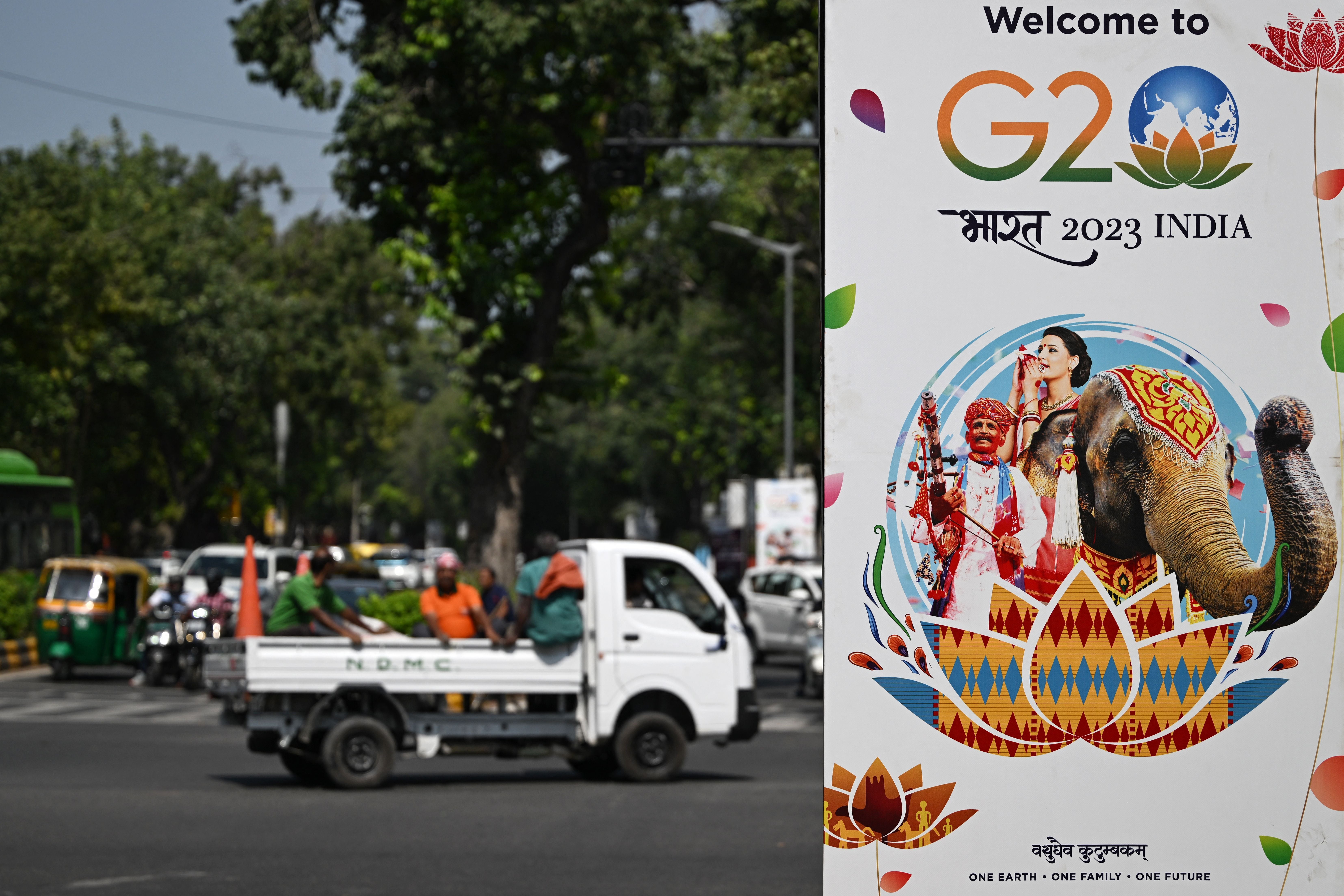 Commuters make their way past a billboard installed along a street ahead of the two-day G20 summit in New Delhi