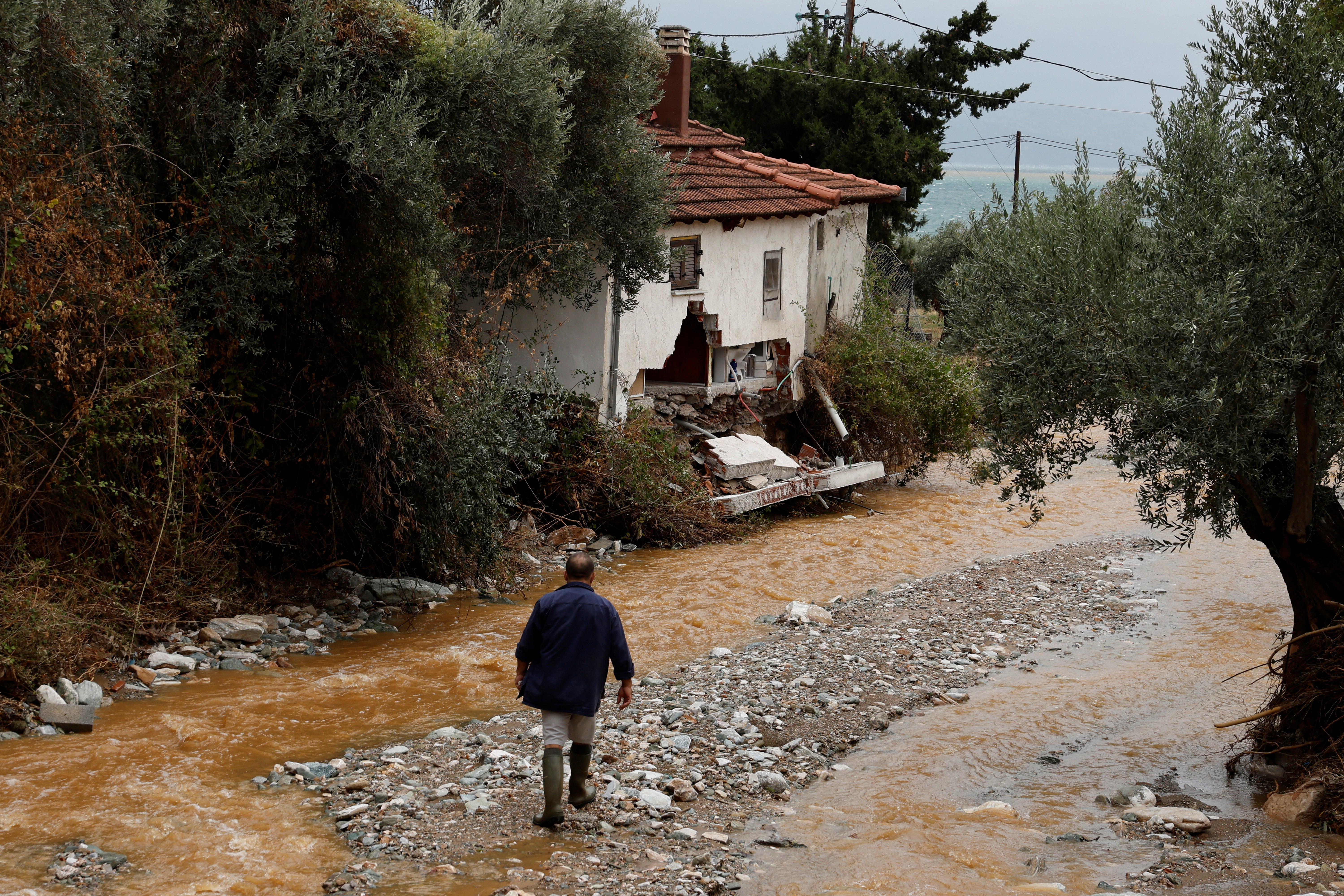 A man walks near a partially destroyed house in Kala Nera village