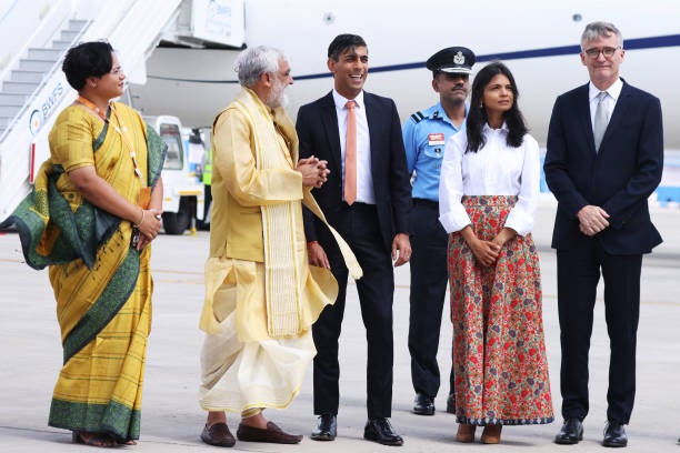 Sunak and his wife Akshata Murty (C) are met on the tarmac by dignitaries including the Indian minister of state