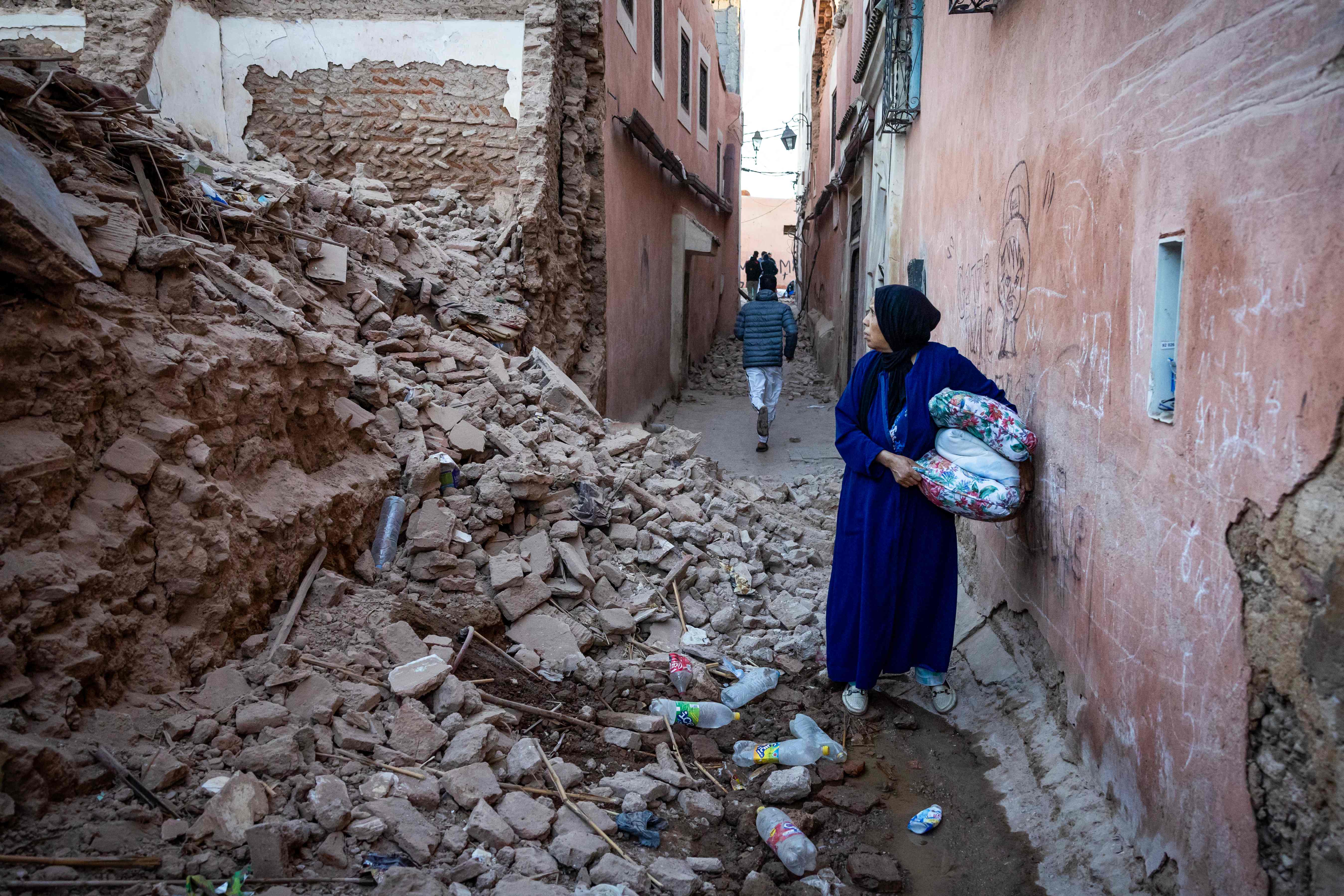 A woman looks at the rubble of a building in the earthquake-damaged old city in Marrakech