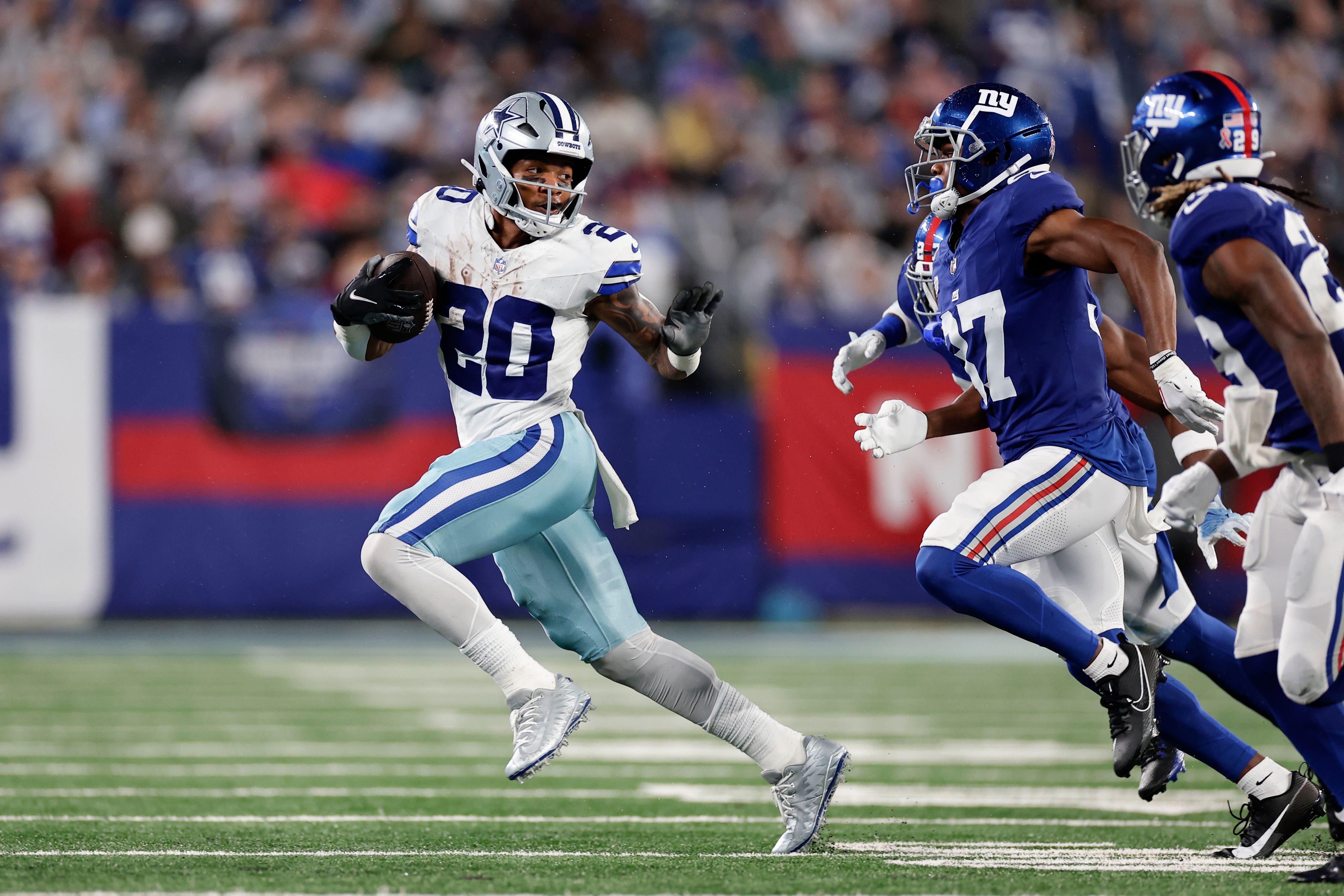 Dallas Cowboys’ Tony Pollard, left, runs the ball during the second half against the New York Giants (Adam Hunger/ AP)