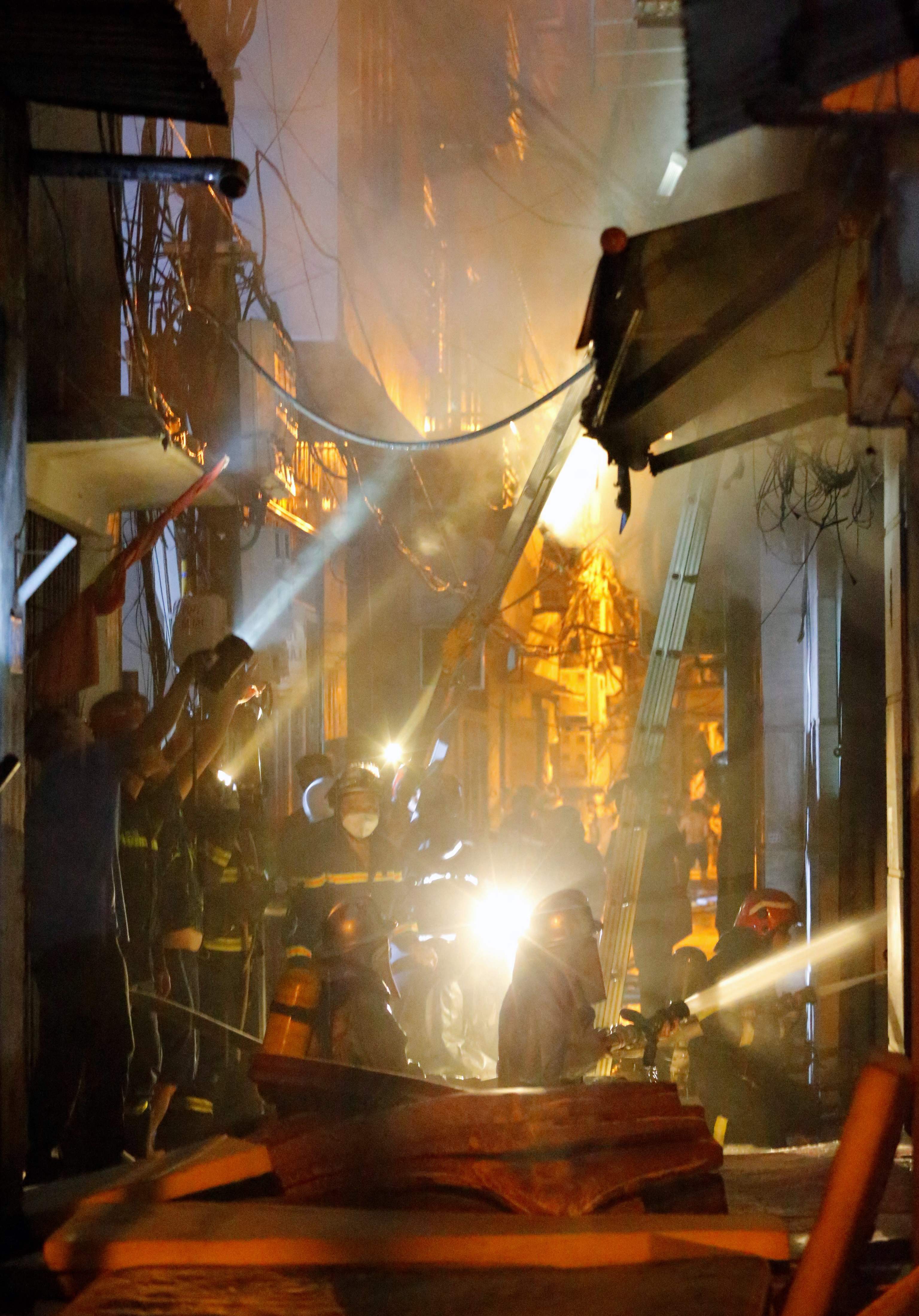 Firefighters work to put out a fire and rescue people at an apartment block in Hanoi