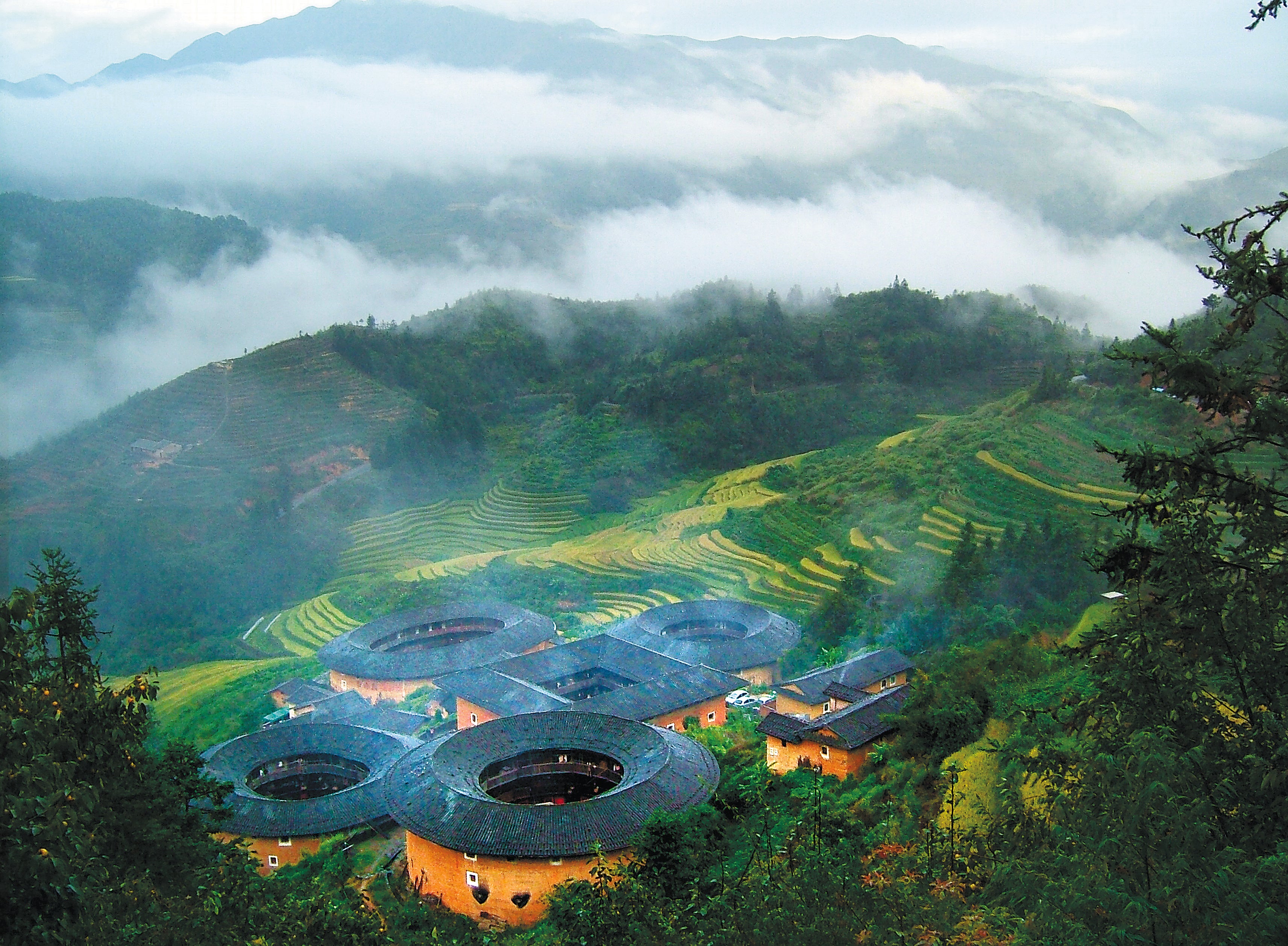 A bird’s eye view of the earthen buildings in Nanjing county, Fujian province, surrounded by forests and tiered farmlands