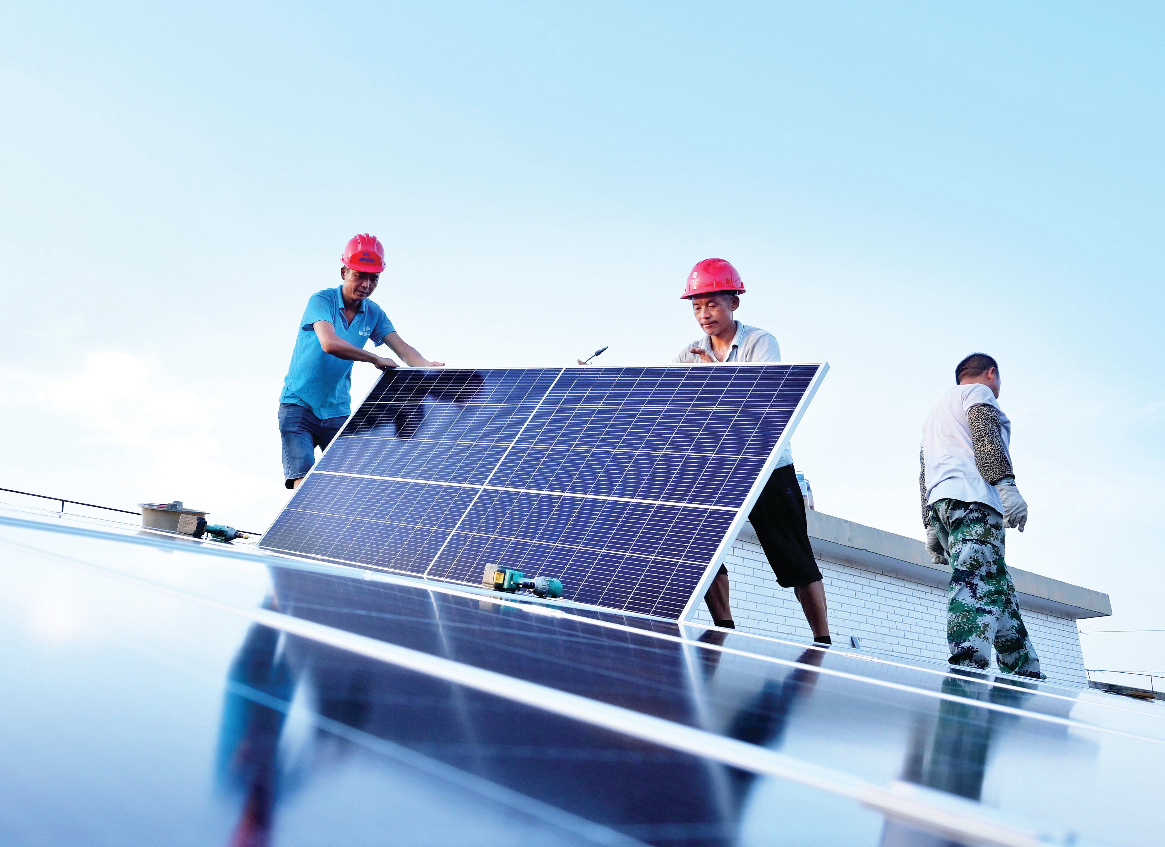 Workers instal solar panels on the roof of an energy cube that was built to provide electricity for residents of Nanjing, Jiangsu province