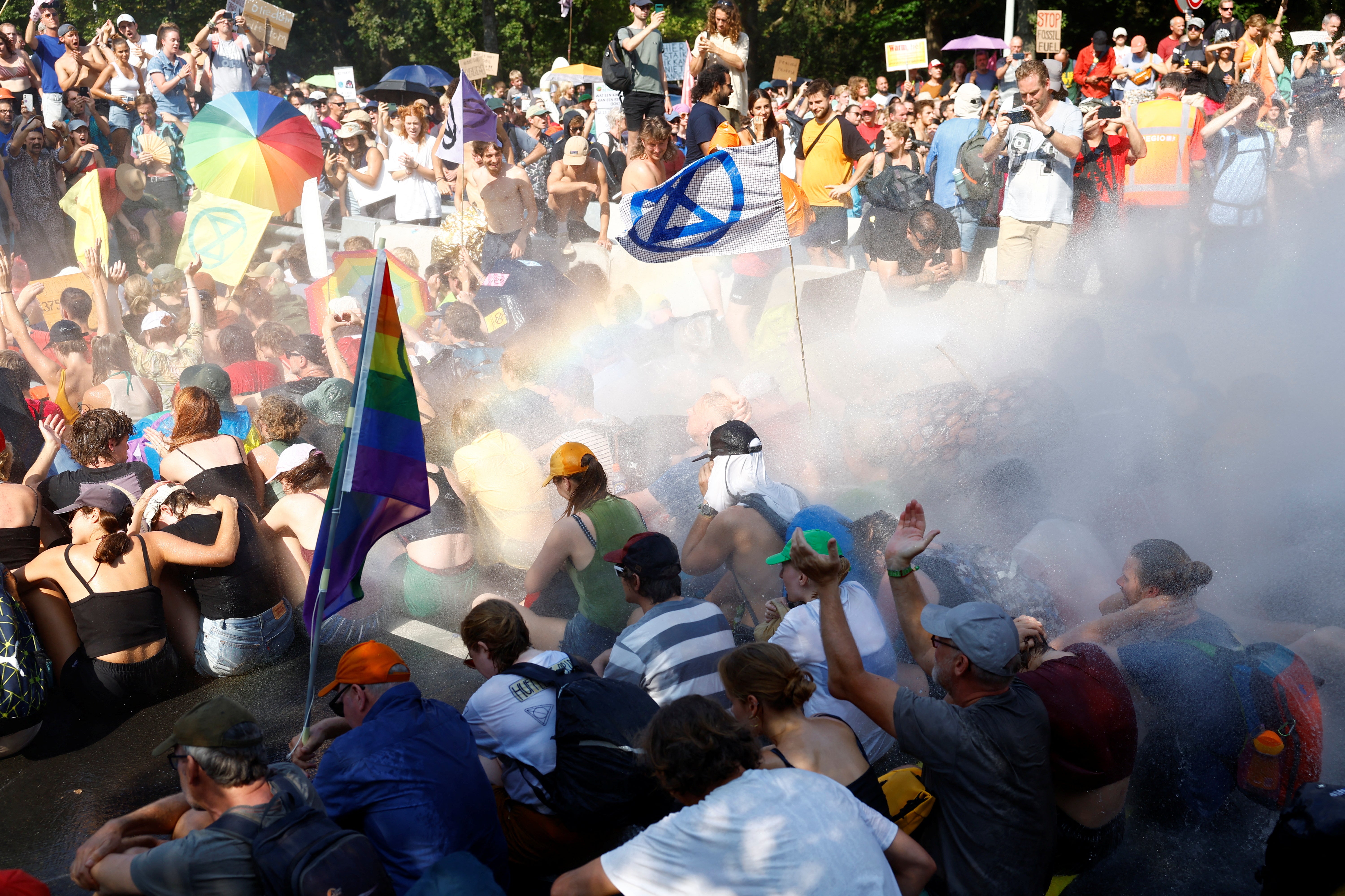 People are sprayed by a water cannon, as climate activists block the A12 highway in The Hague, Netherlands