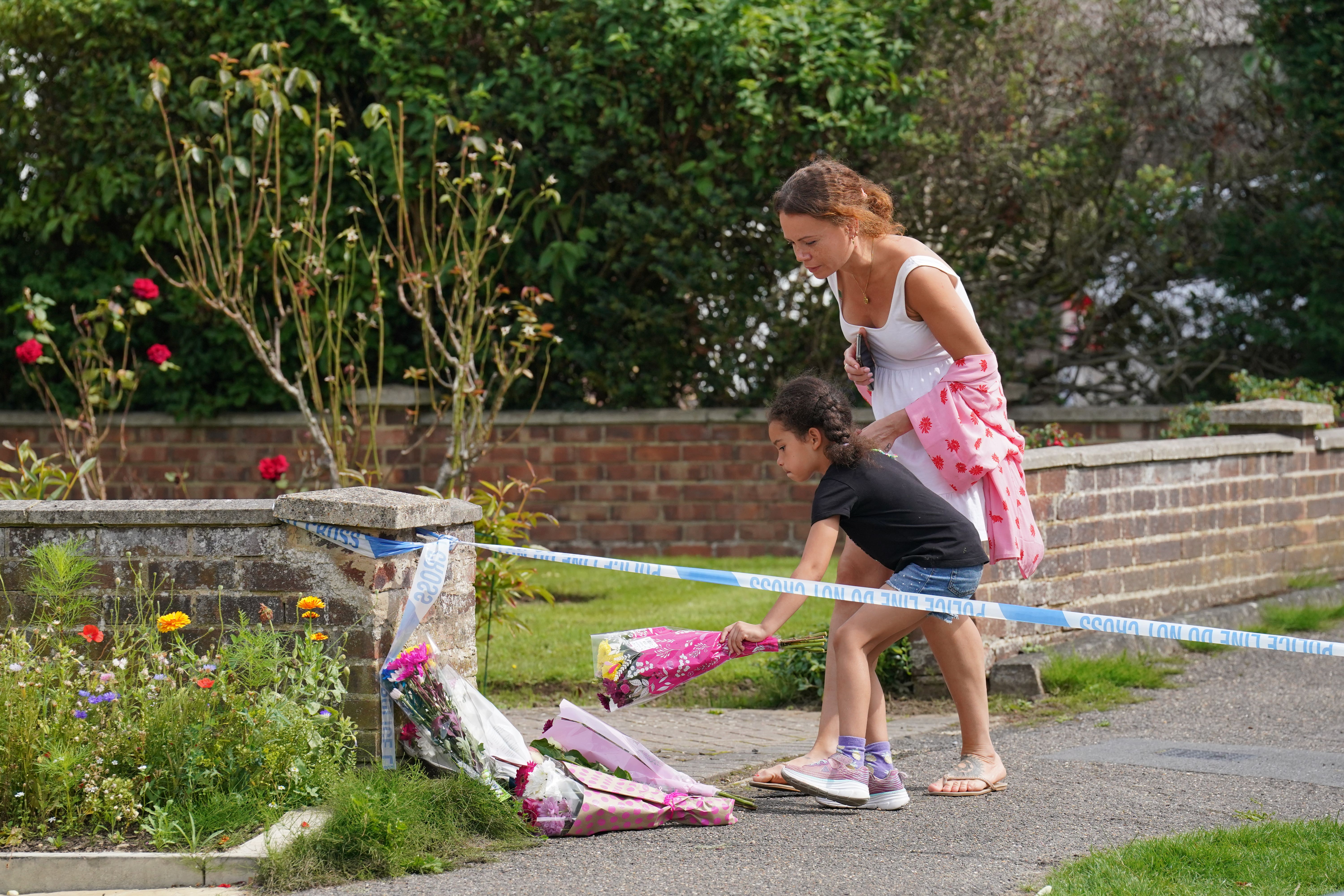 People lay flowers outside the property on Hammond Road in Woking (Jonathan Brady/PA)