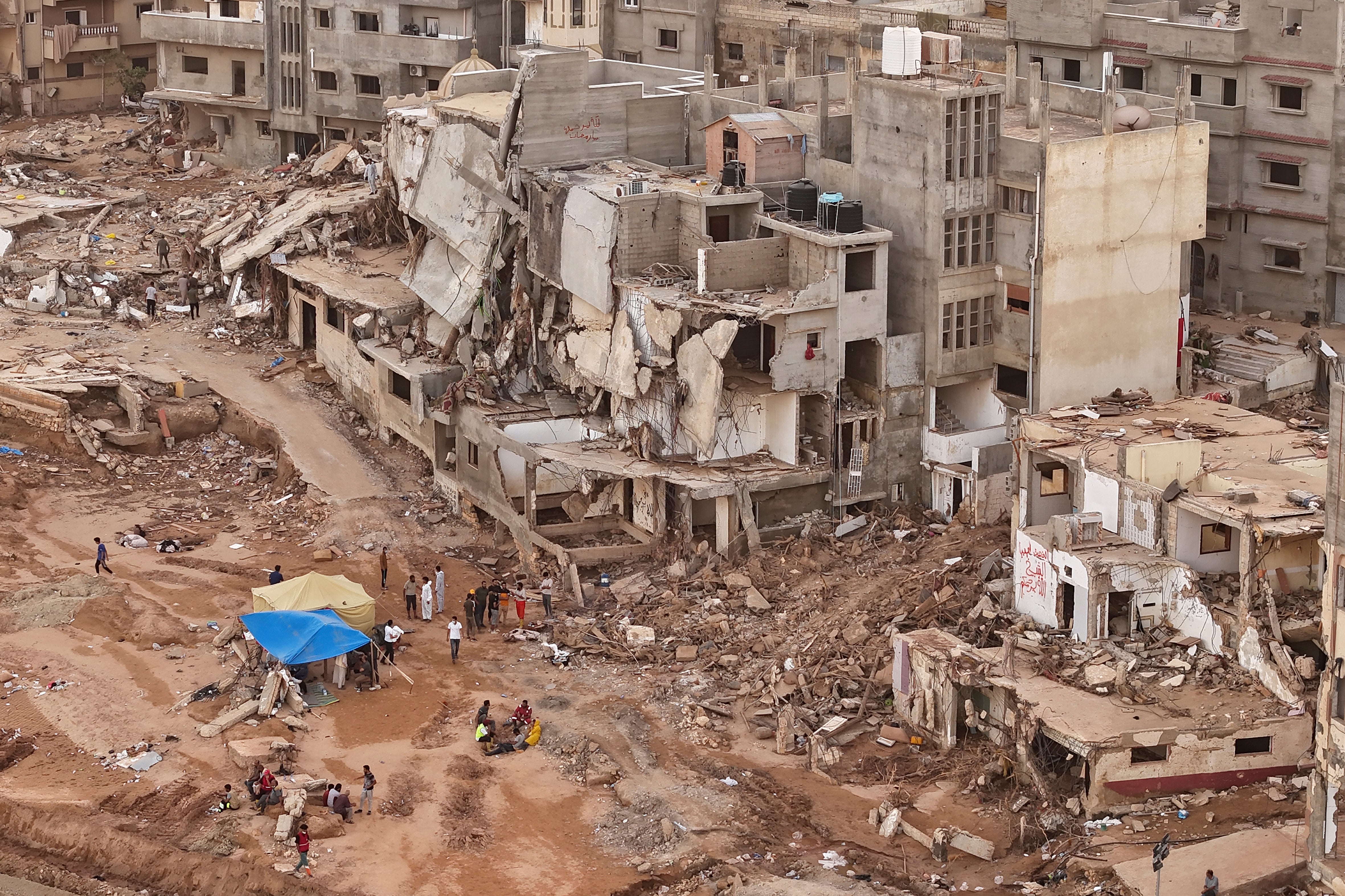 Rescuers and relatives sit in front of collapsed buildings after recent flooding caused by Mediterranean storm Daniel, in Derna