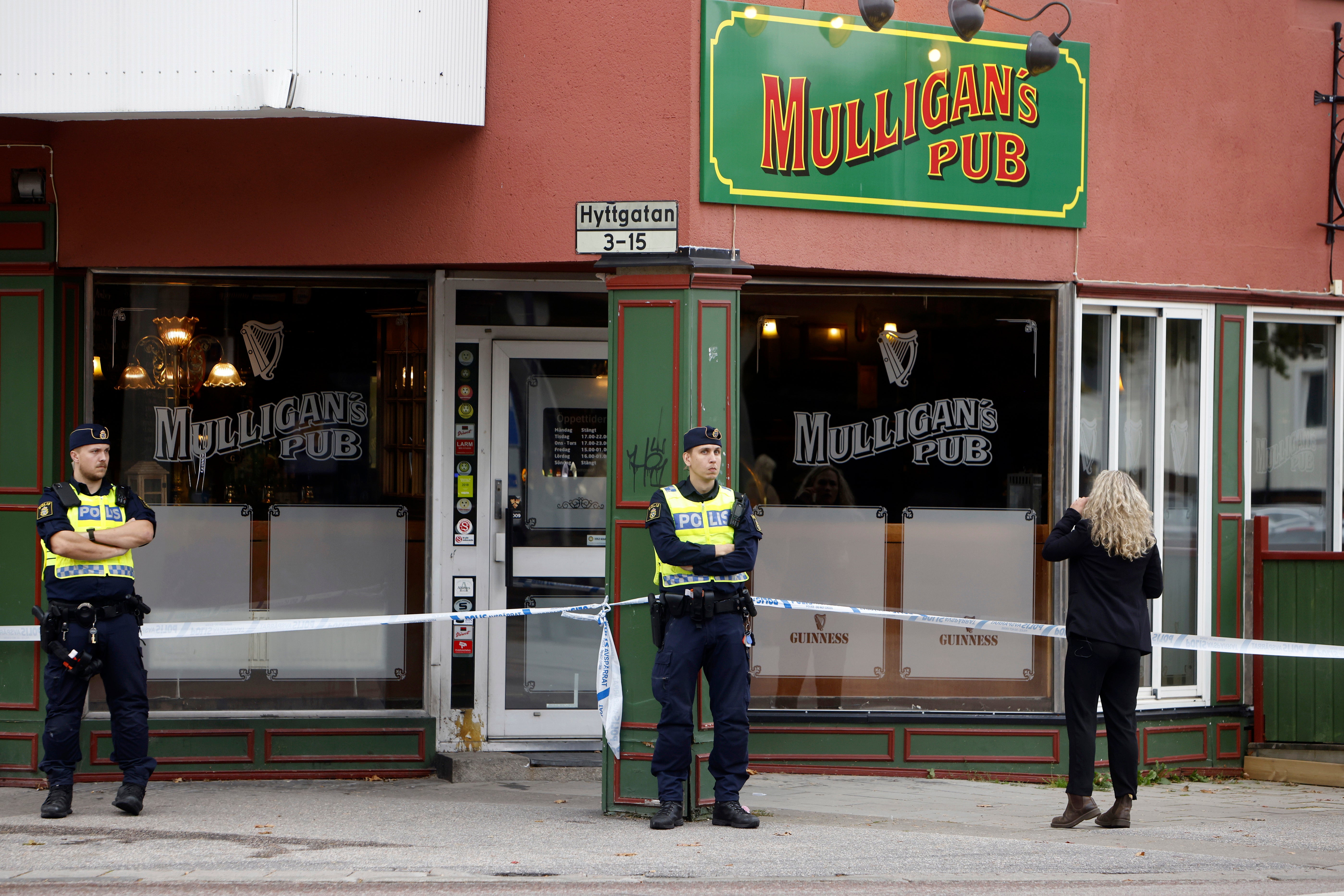 Police stand outside a pub where two people were killed and two wounded following a shooting, in Sandviken