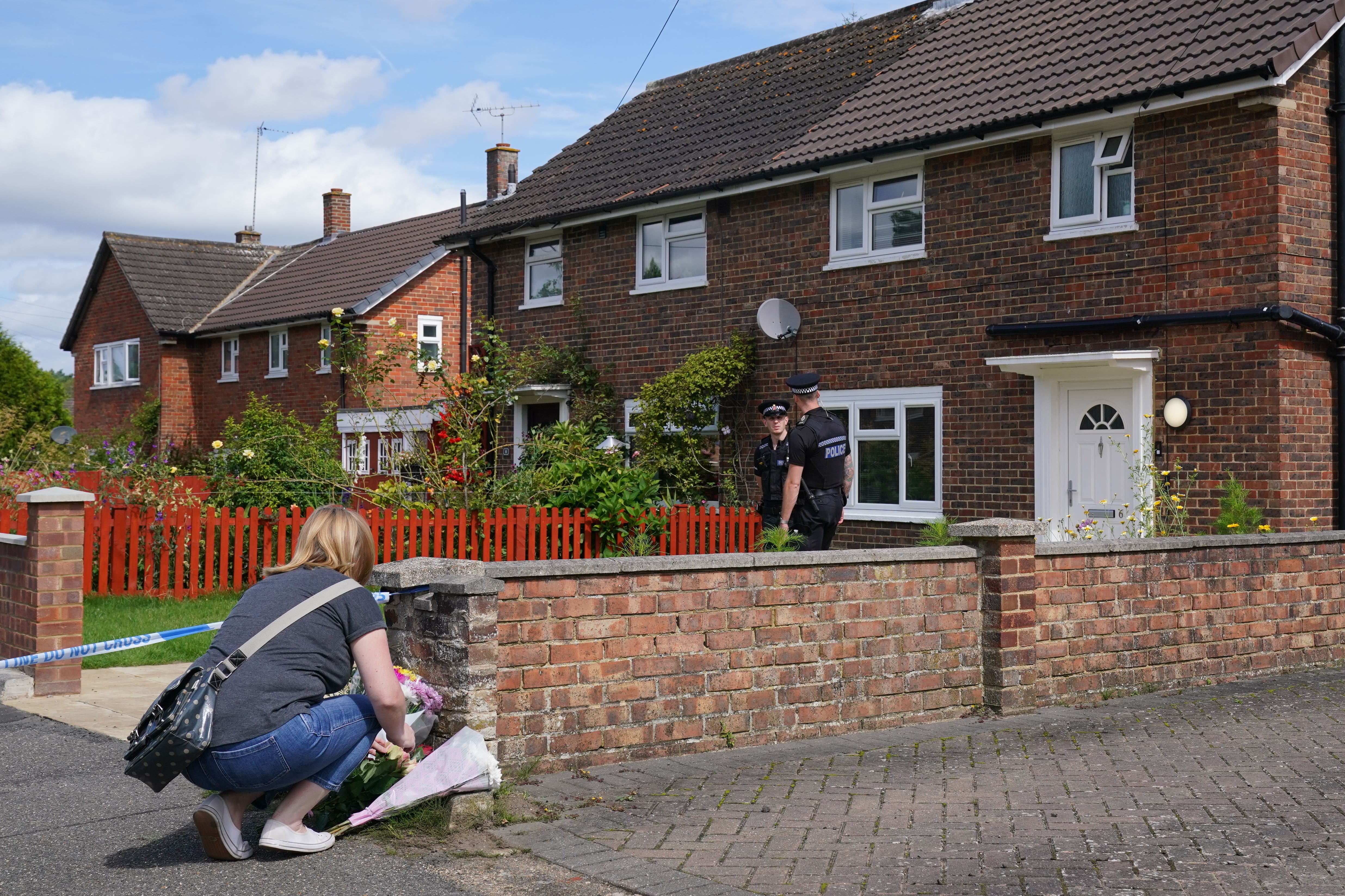 A person leaves flowers outside the property on Hammond Road in Woking (Jonathan Brady/PA)