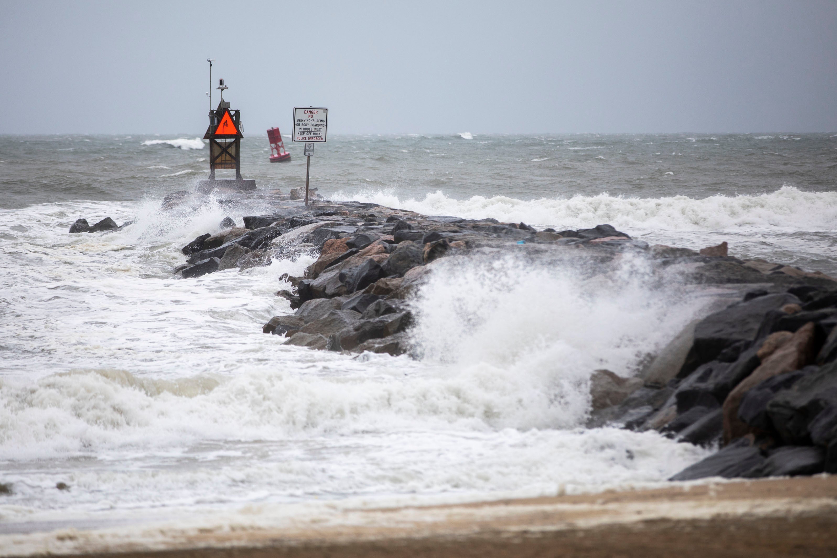 Waves break along the jetty at Rudee Inlet in Virginia Beach, Virginia on Friday