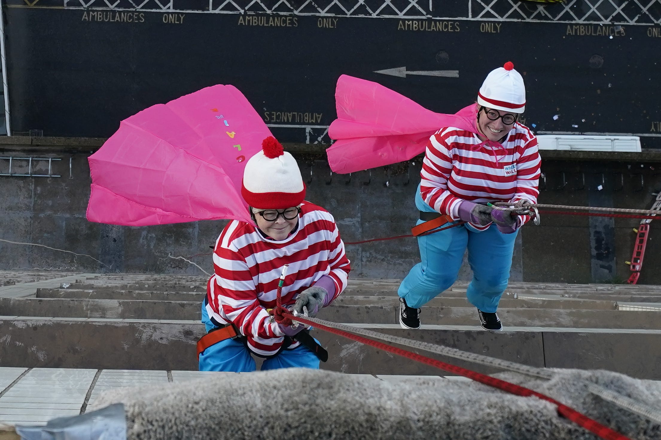 Claire Stork, (left) abseils down the front of St Thomas’ Hospital in London (Aaron Chown/PA)