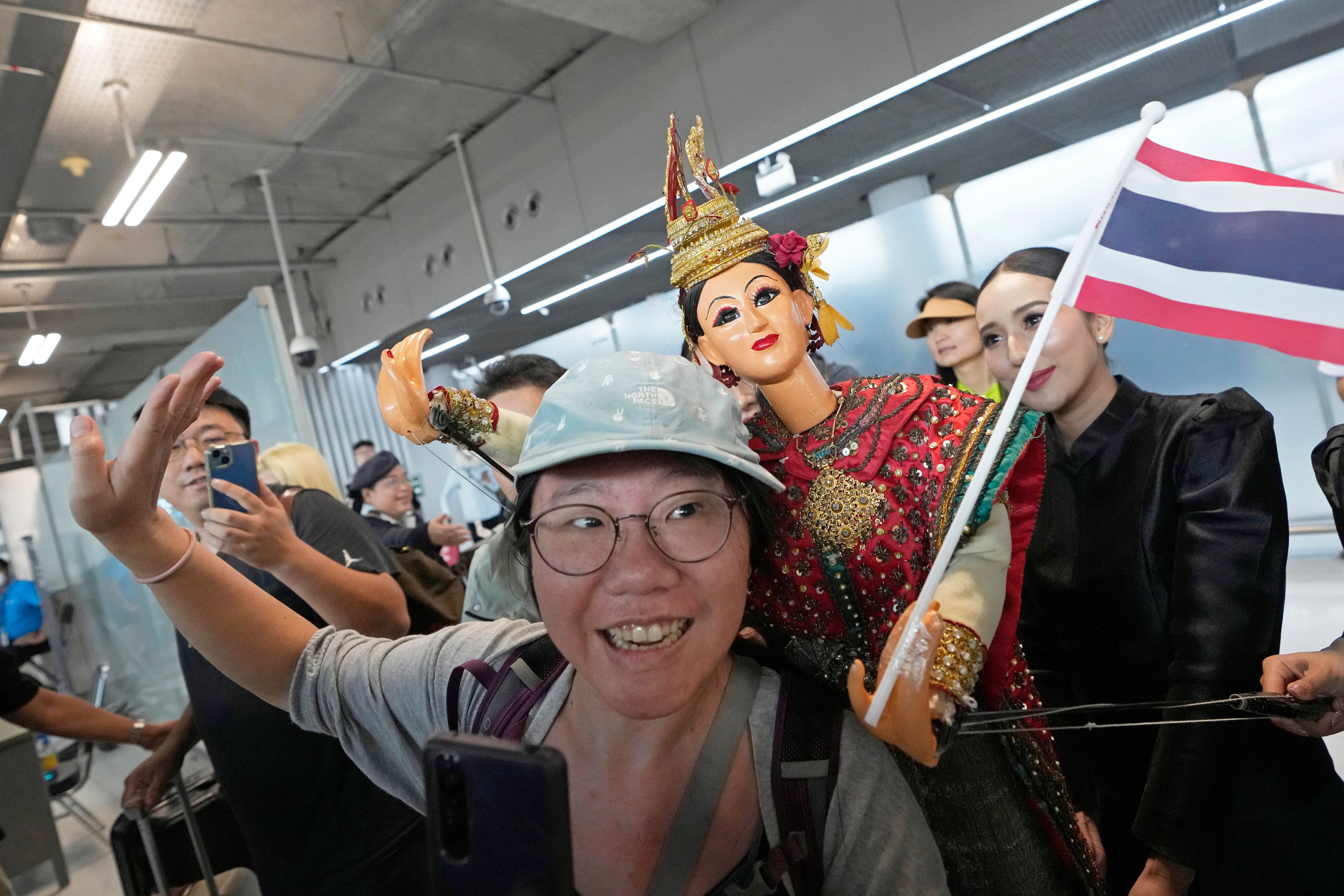 Chinese tourists dance with puppet as Chinese tourists are welcomed on the arrivals at Suvarnabhumi International Airport in Samut Prakarn province, Thailand, Monday, Sept. 25, 2023
