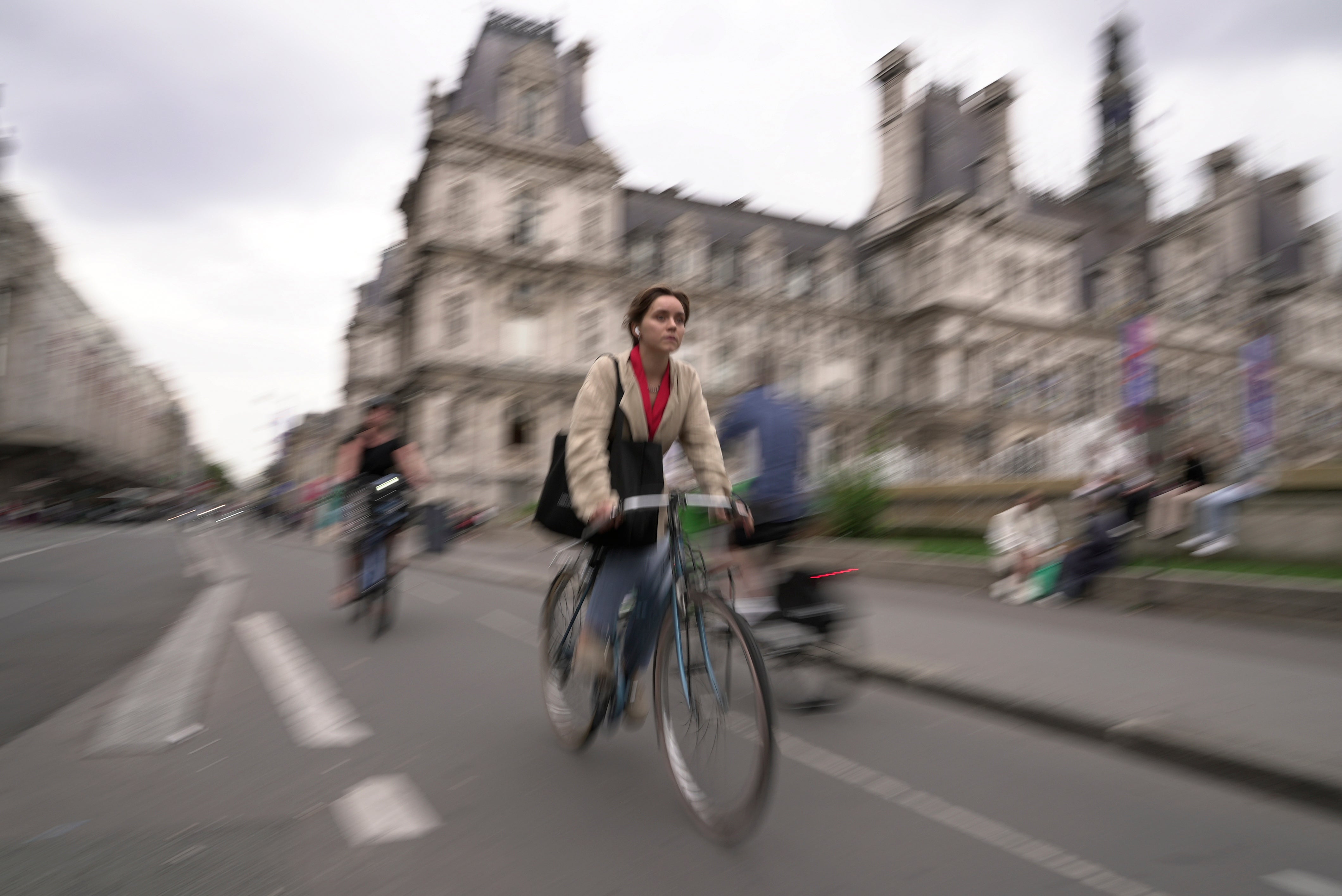 A woman rides a bike past Paris City Hall